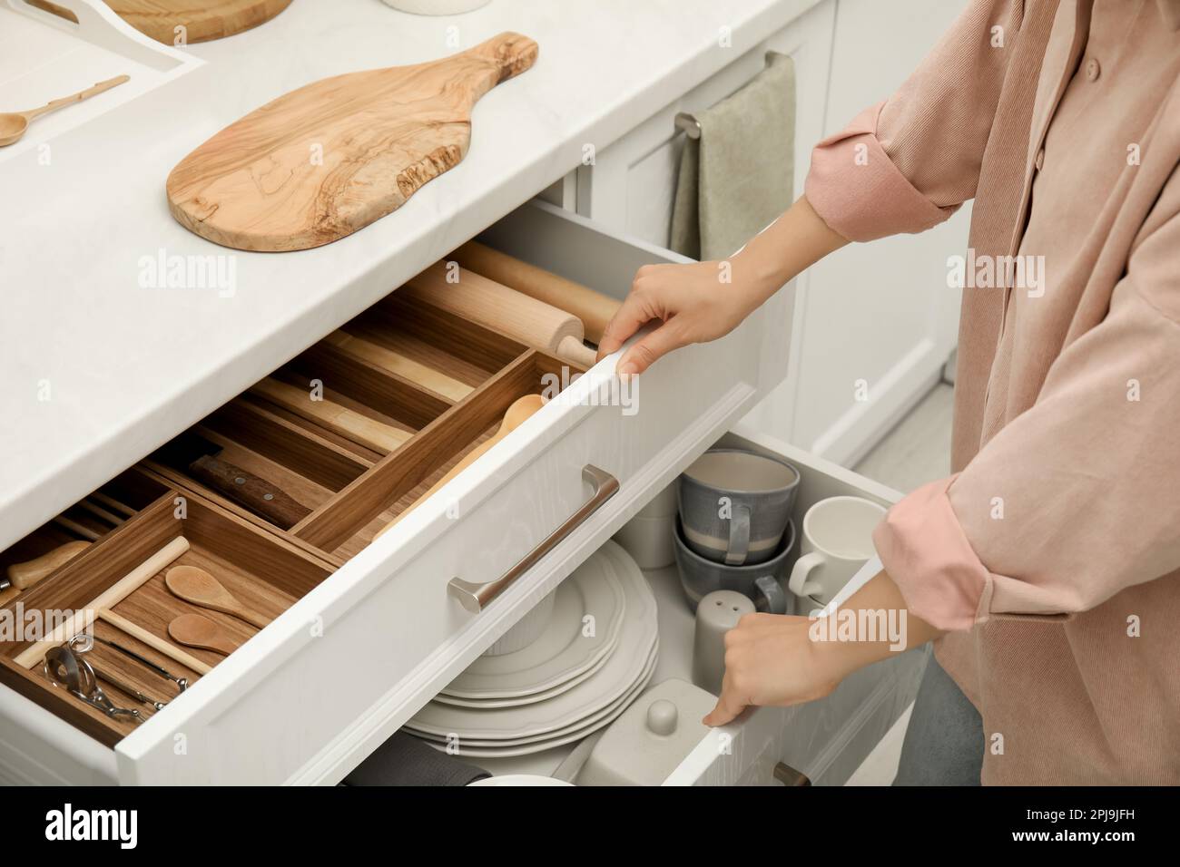 Femme ouvrant les tiroirs de l'armoire de cuisine avec différents  ustensiles et vaisselle, gros plan Photo Stock - Alamy