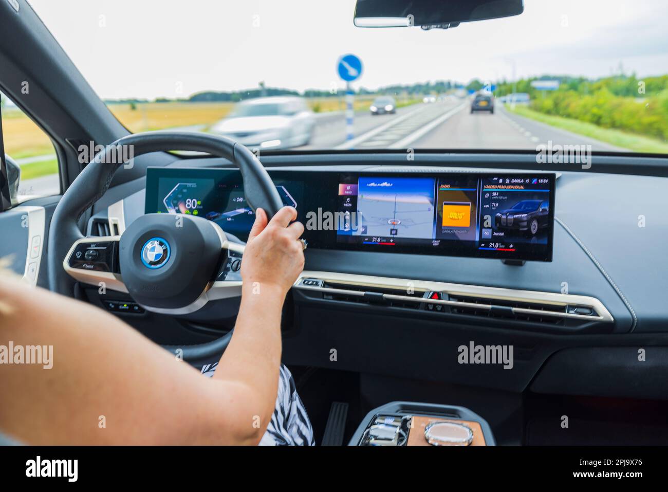 Belle vue chère de l'intérieur de la BMW iX40 voiture électrique conduite par une femme conducteur sur l'autoroute. Suède. Banque D'Images