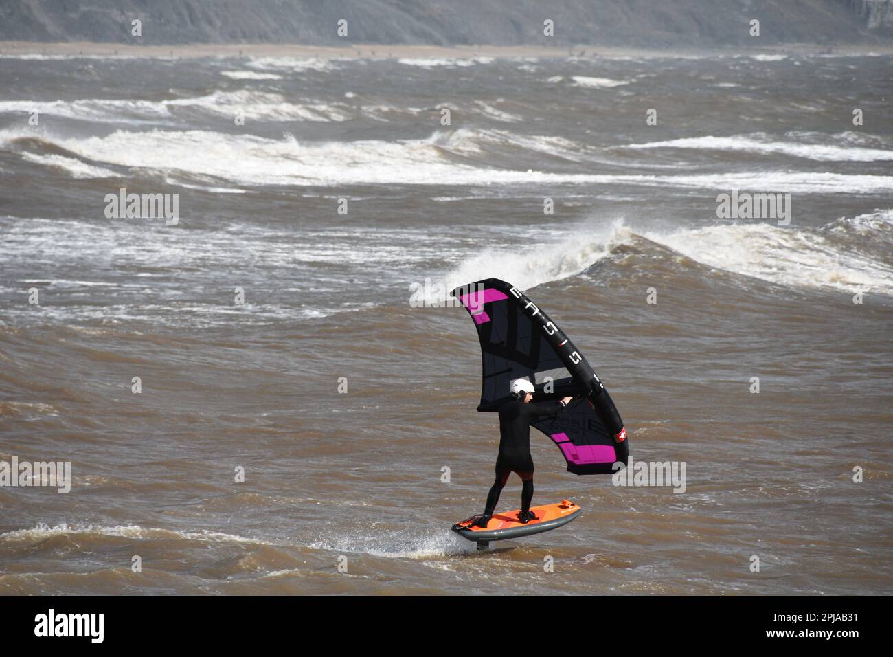 Une planche de surf d'aile glisse à travers une mer saccadée alimentée par une brise raide au large de la côte jurasique dans la baie de Lyme. Dorset.UK Banque D'Images