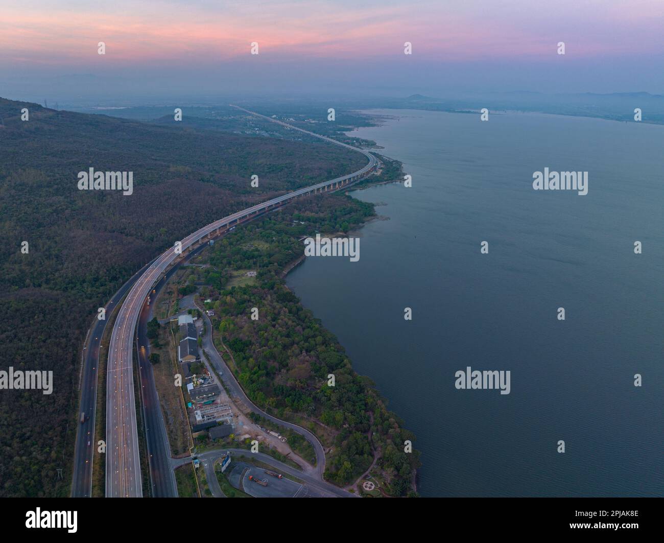 Vue aérienne lumière sur la super autoroute le long du barrage Lam Takhong au crépuscule. vue sur le paysage naturel au bord de la route. barrages et éoliennes qui généraat Banque D'Images