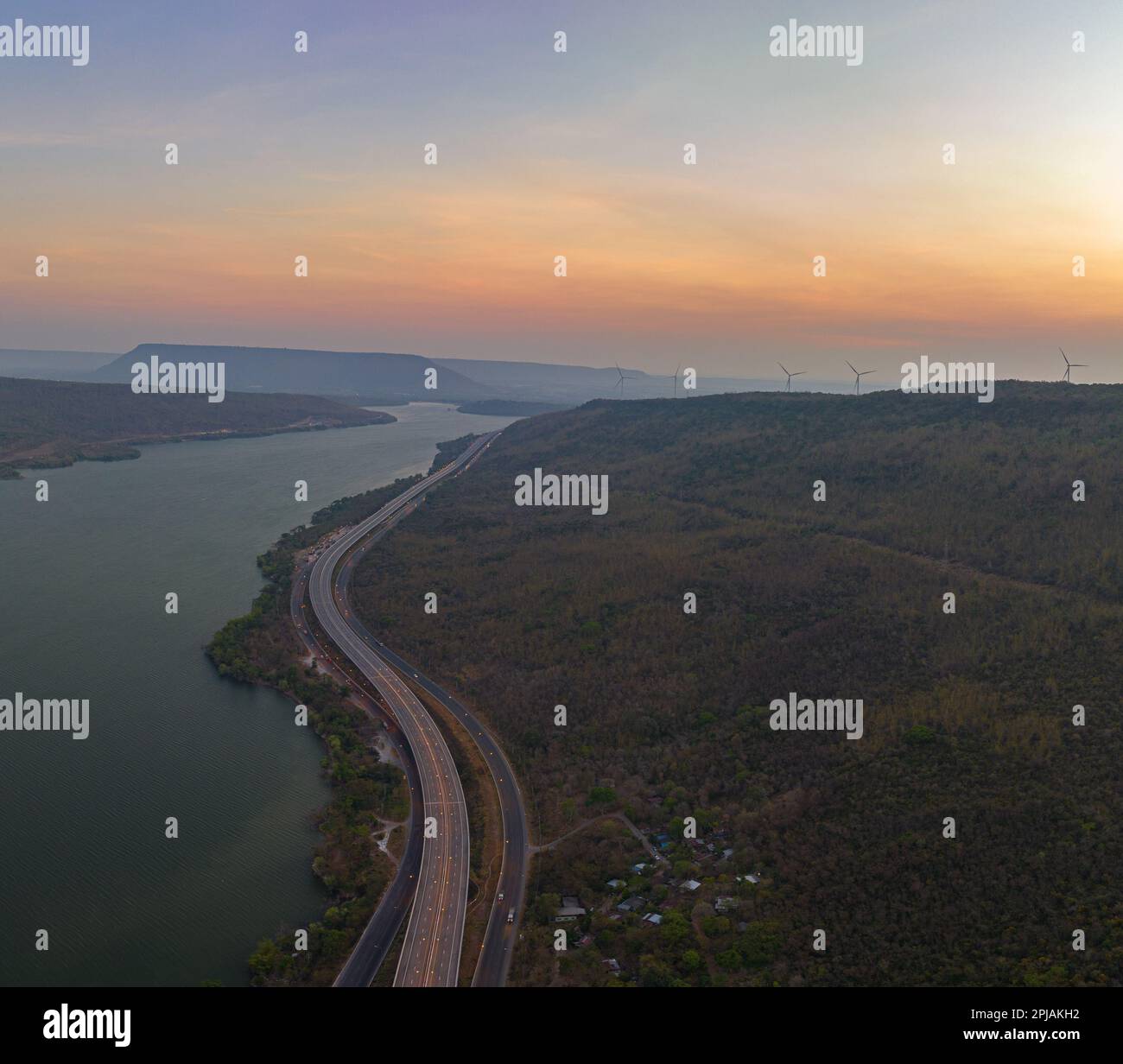 Vue aérienne lumière sur la super autoroute le long du barrage Lam Takhong au crépuscule. vue sur le paysage naturel au bord de la route. barrages et éoliennes qui généraat Banque D'Images