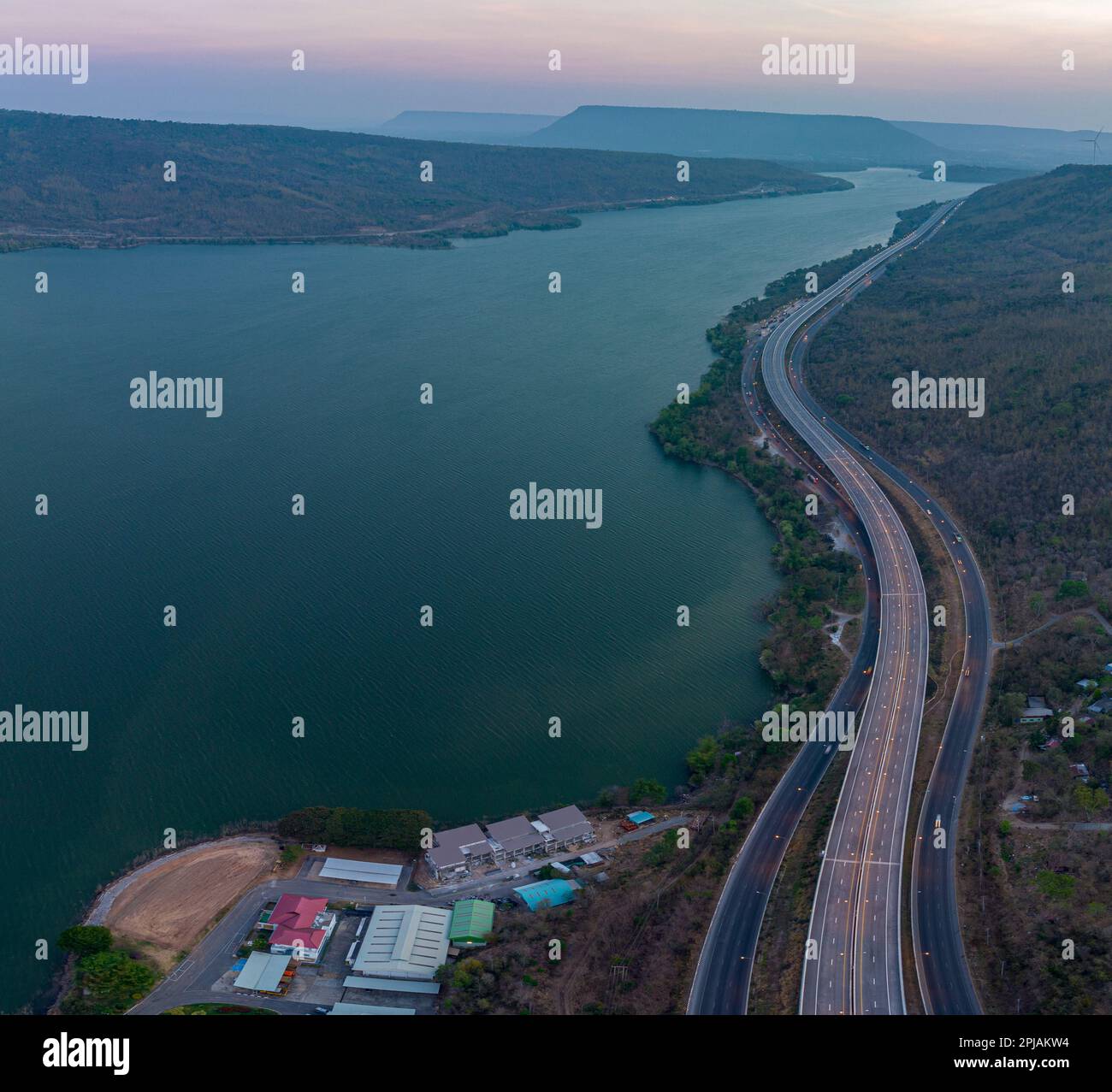 Vue aérienne lumière sur la super autoroute le long du barrage Lam Takhong au crépuscule. vue sur le paysage naturel au bord de la route. barrages et éoliennes qui généraat Banque D'Images