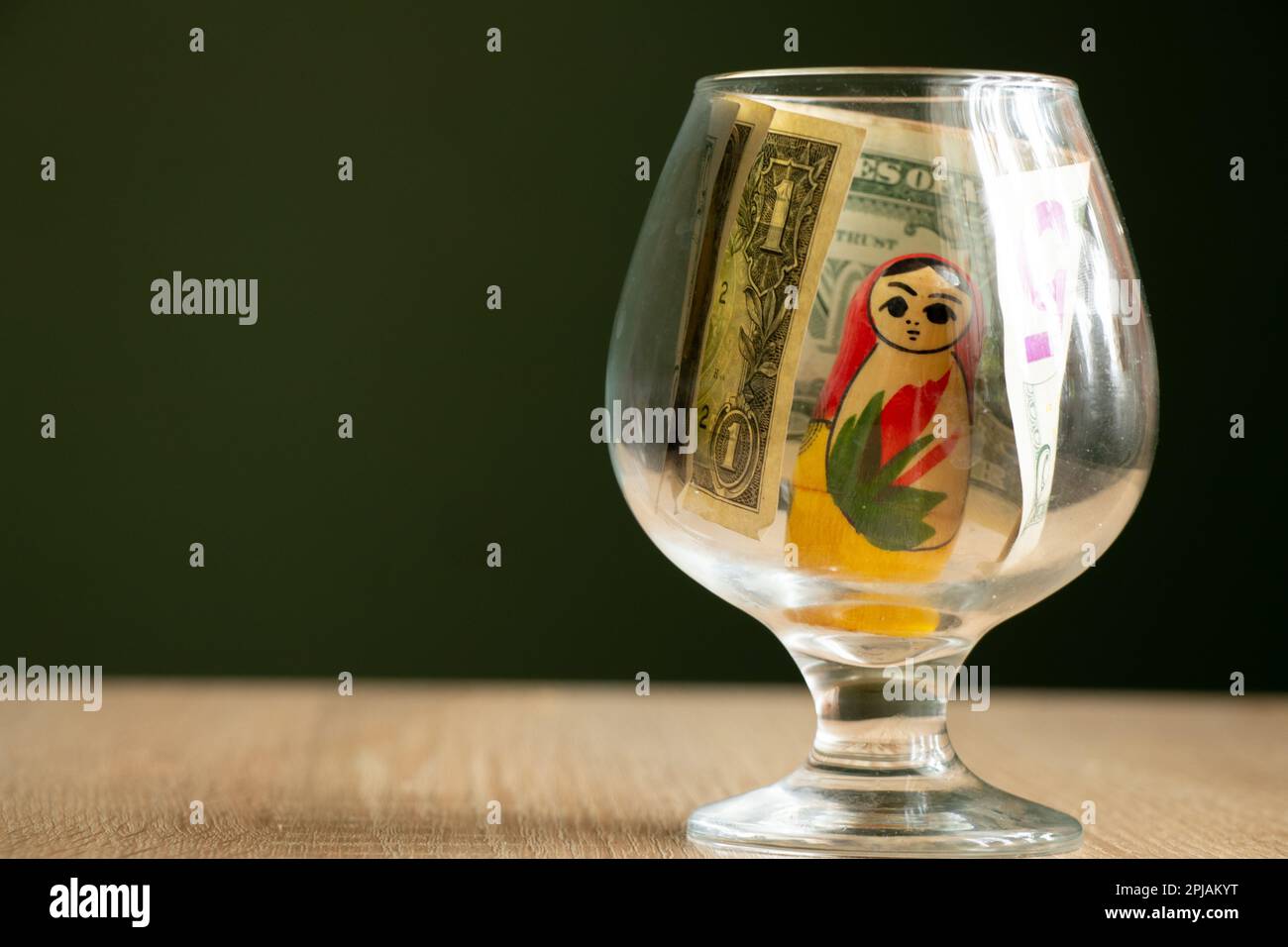 poupée russe en bois et dollars dans une tasse de verre sur la table Banque D'Images
