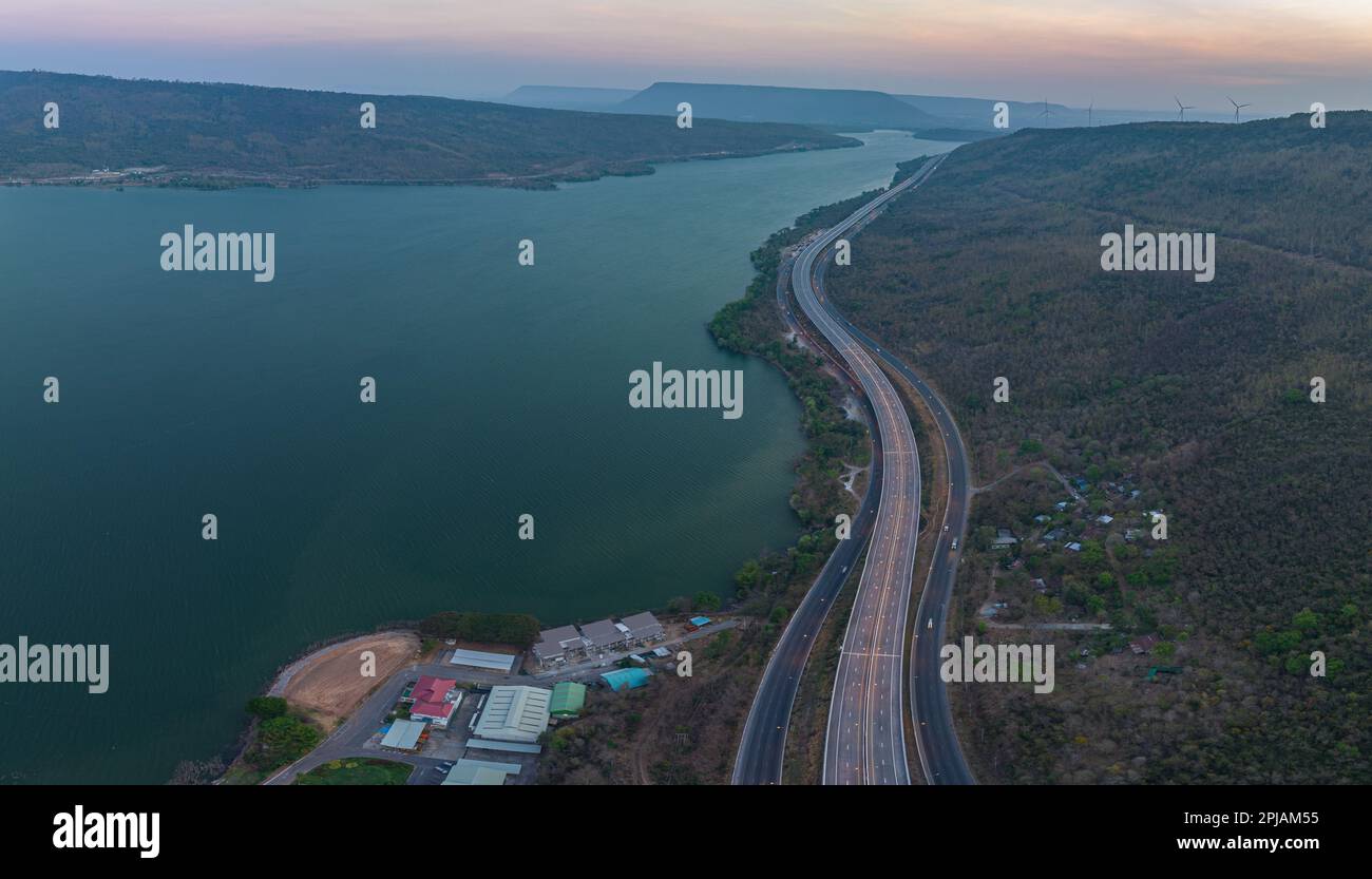 Vue aérienne lumière sur la super autoroute le long du barrage Lam Takhong au crépuscule. vue sur le paysage naturel au bord de la route. barrages et éoliennes qui généraat Banque D'Images