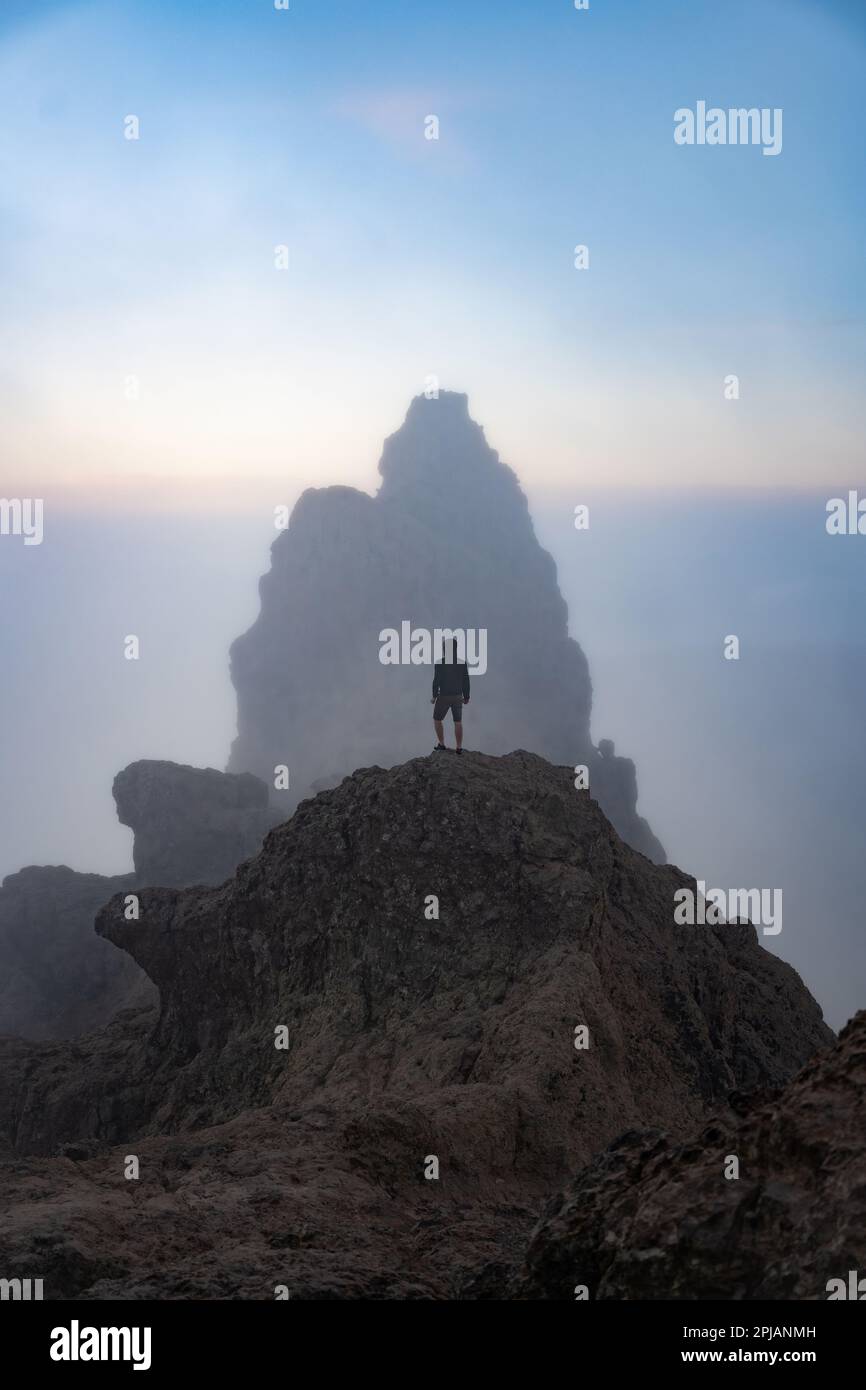 Vue imprenable sur une personne au sommet d'une formation rocheuse pendant un beau lever de soleil. Pico de las Nieves, Grande Canarie, Îles Canaries, Espagne. Banque D'Images