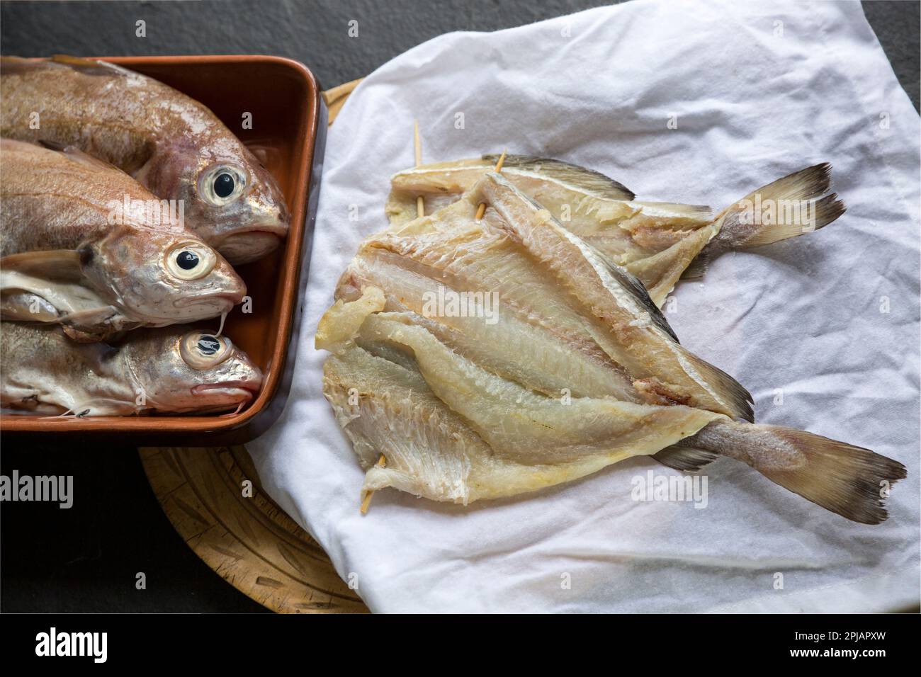 Pouding maison salé et séché, Trisopterus luscus, qui sera utilisé pour faire le plat connu sous le nom de brandade. Des poufs frais peuvent être vus sur la gauche ogf le Banque D'Images