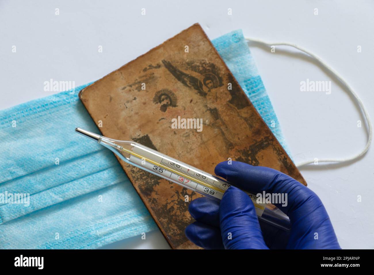 Thermomètre en verre et main dans un gant bleu sur le fond du masque Medetsyn Banque D'Images