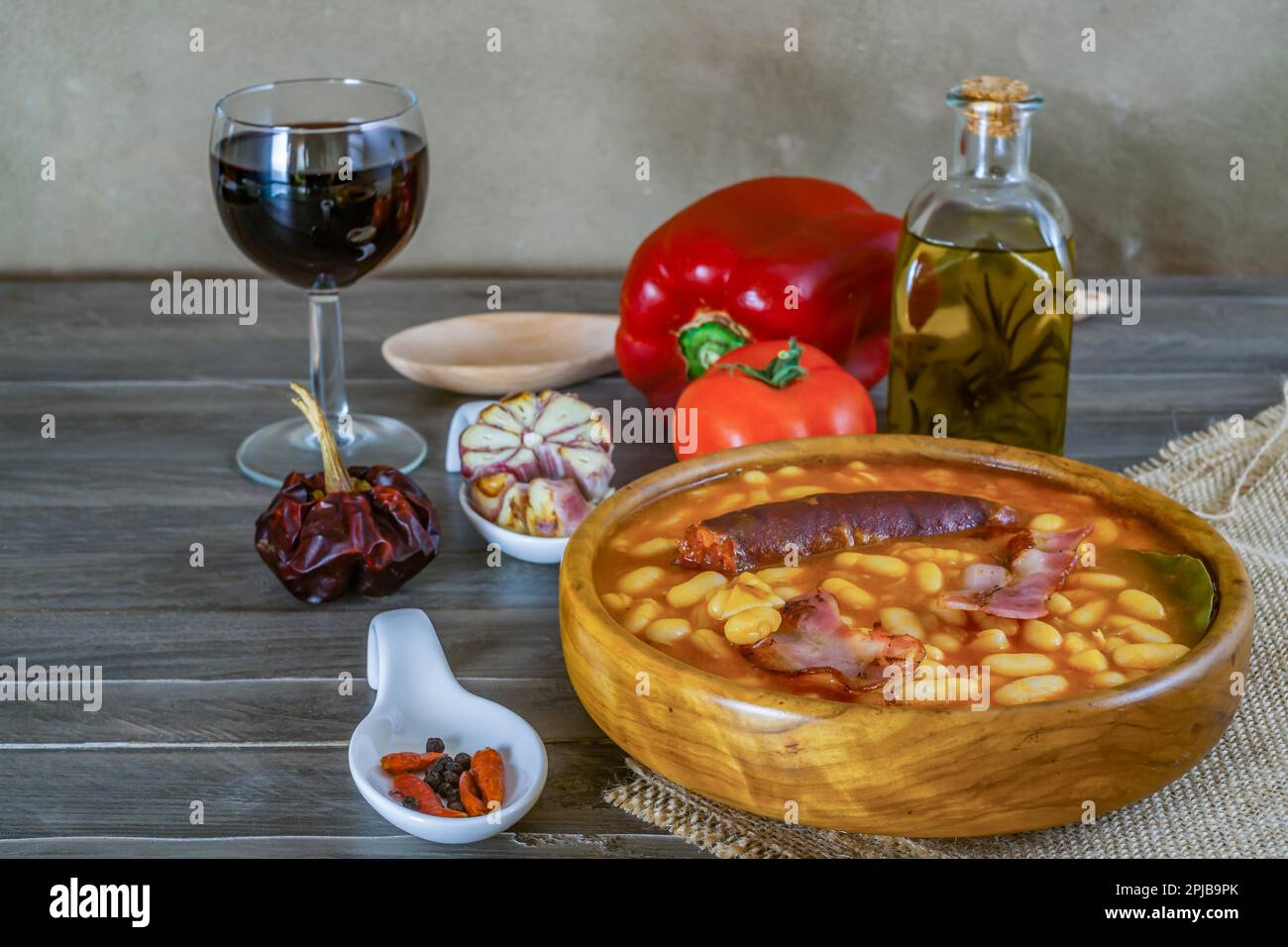 Haricots blancs cuits avec du bacon et du chorizo dans un bol en bois avec tous ses ingrédients Banque D'Images