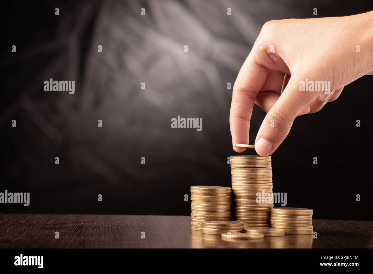 La main féminine a mis la pièce dans la pile, l'investissement d'argent et le concept de fonds futur Banque D'Images