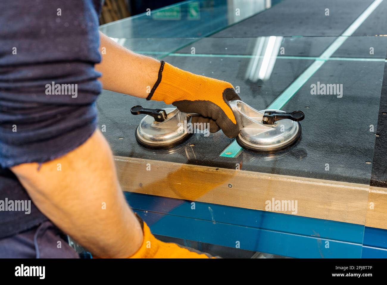 Un vitrier dans une usine de verre enlève le verre lourd à l'aide de ventouses, outils industriels spécialisés Banque D'Images
