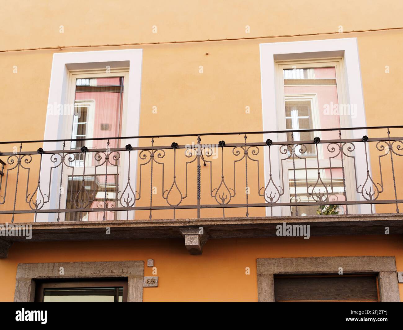 Résumé gros plan d'un balcon et de fenêtres avec réflexion sur une maison de rendu orange à Aoste, Vallée d'Aoste, Italie Banque D'Images