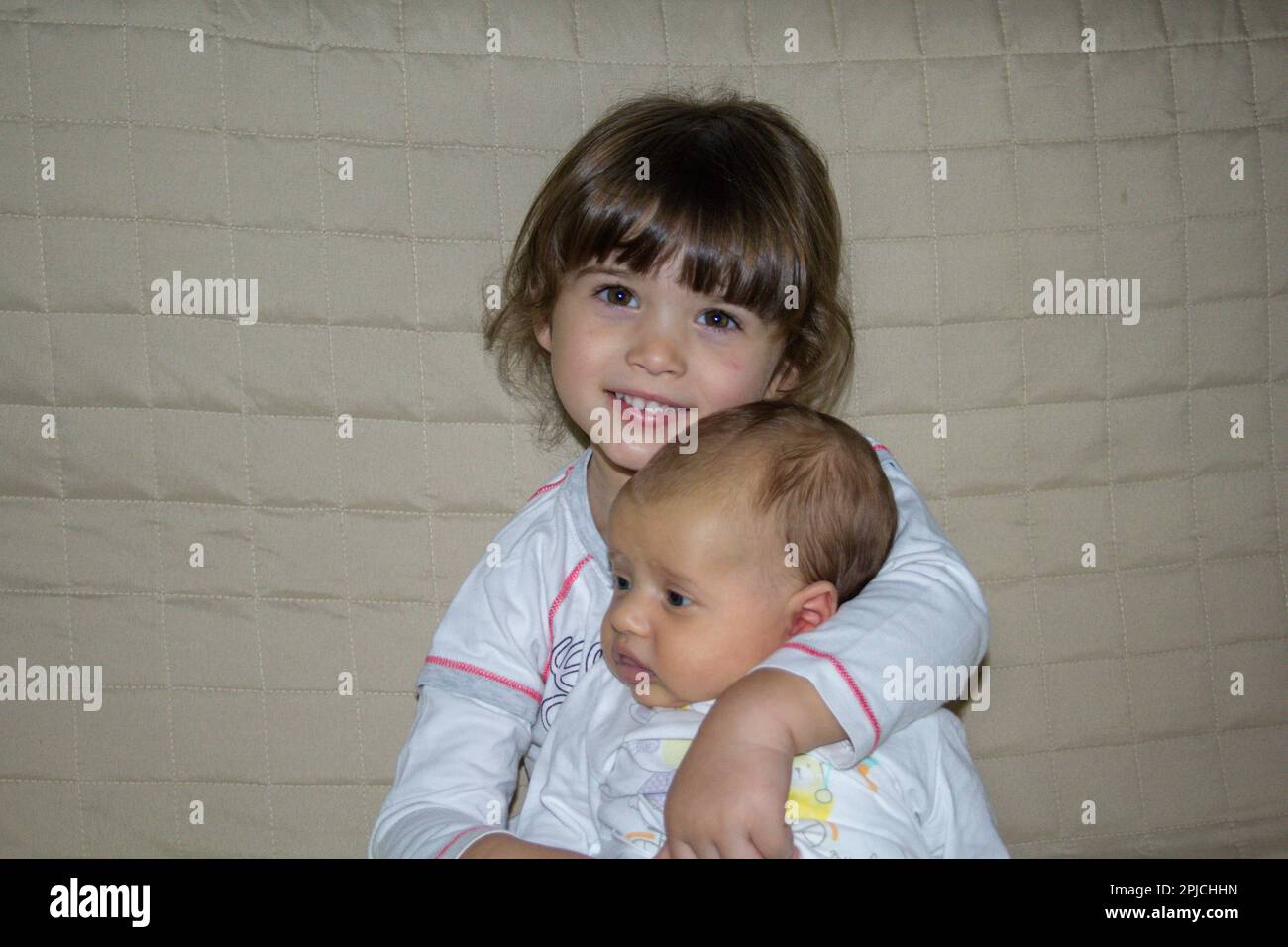 Image d'une adorable petite fille souriante embrassant son nouveau-né frère. Référence à l'amour fraternel. Banque D'Images