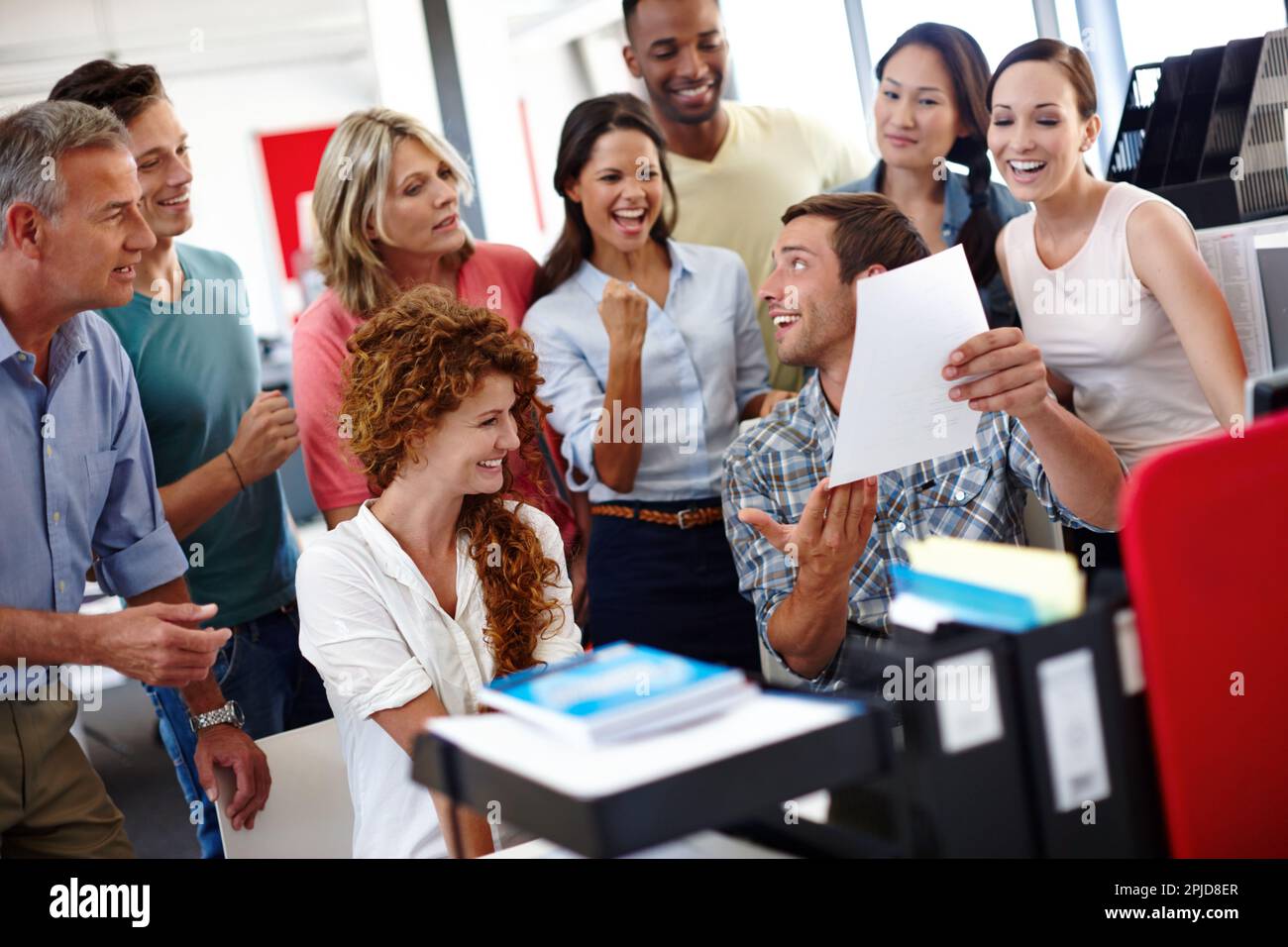 Nous avons atteint notre date limite. un jeune homme montrant quelque chose à ses collègues au bureau. Banque D'Images