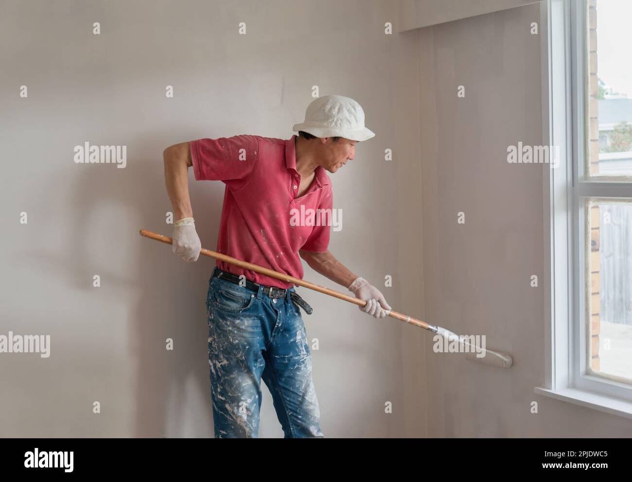 Homme peinture mur avec un rouleau dans le projet de rénovation de maison. Auckland. Banque D'Images