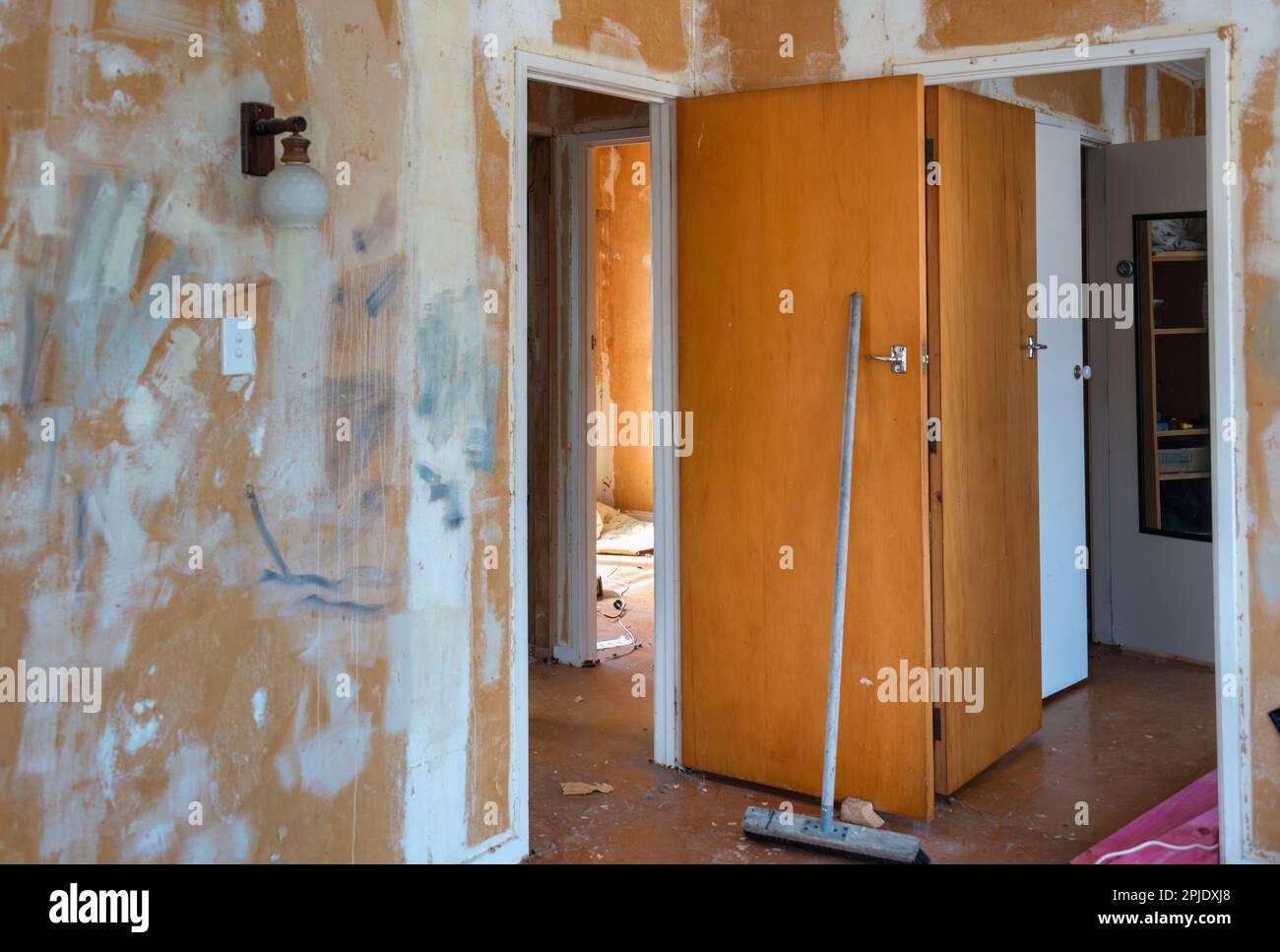 Vieille maison rayée de papier peint et de placoplâtre. Balai appuyé sur la porte. Projet de rénovation de la maison. Banque D'Images