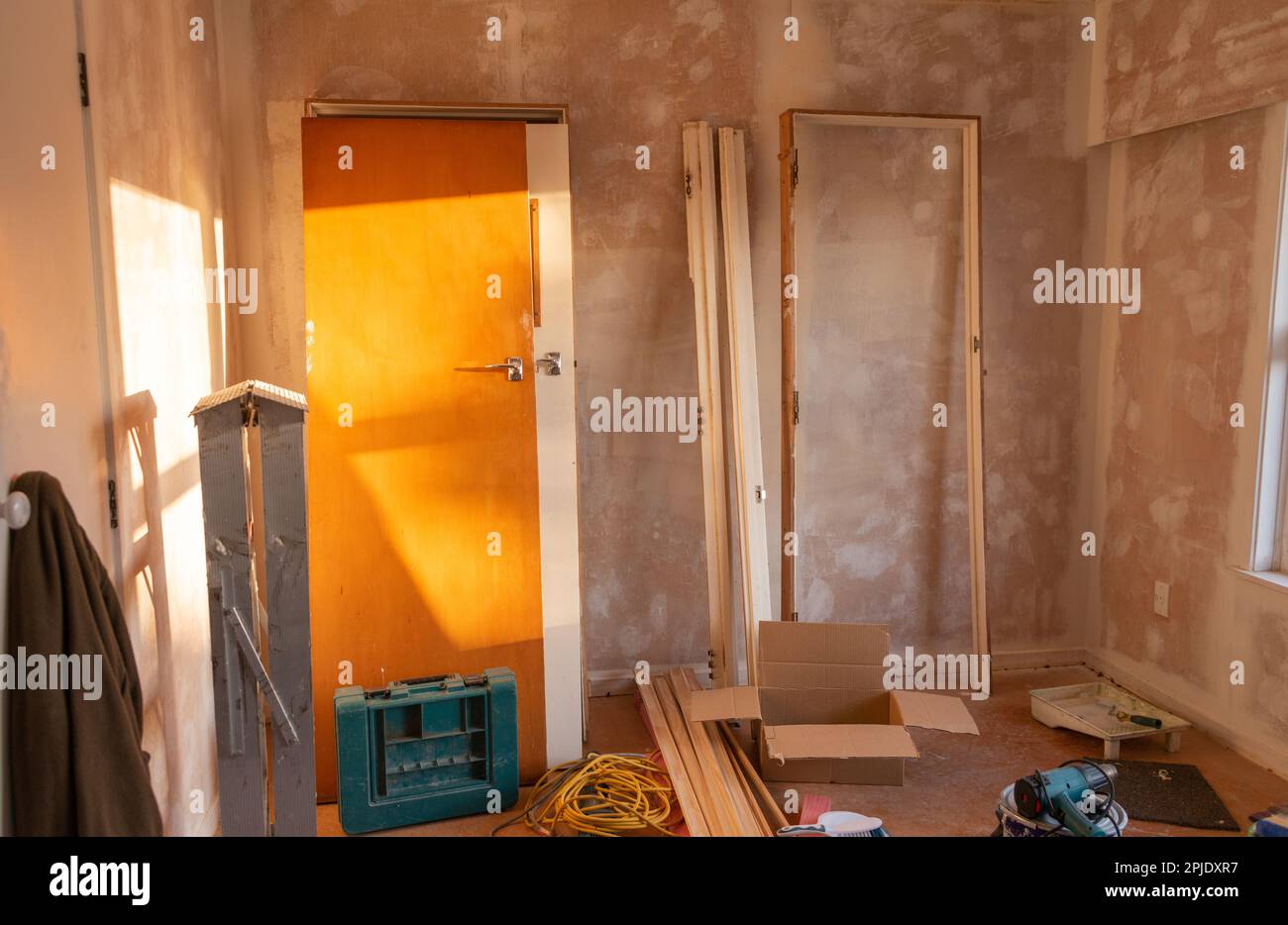 Portes et cadres de porte inclinés sur le mur. Échelle et outils se trouvant autour de la pièce. Projet de rénovation de la maison. Auckland. Banque D'Images