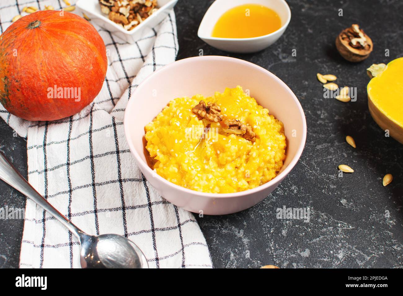 Lait de riz porridge de citrouille avec noix, beurre et miel sur une table en pierre noire. Une alimentation saine. Banque D'Images