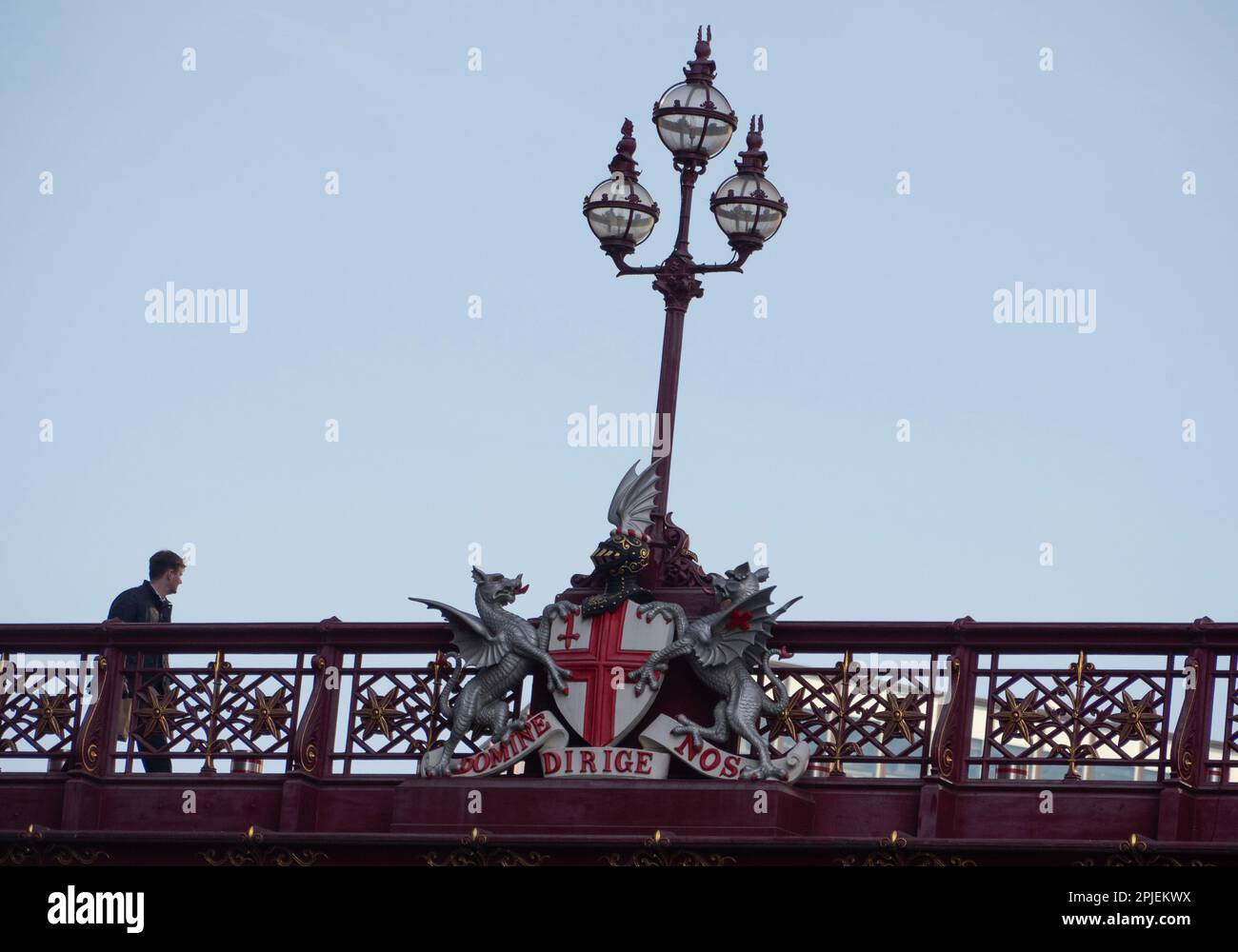 Londres, Royaume-Uni. 8 février 2023. Un piéton traverse le pont routier orné du viaduc Holborn, qui enjambe la vallée de Farringdon Street. La scène présente un lampadaire central à trois têtes décoré des armoiries de la City of London. La devise latine inscrite sur les armes, 'domine Dirige nos', se traduit par 'Seigneur, guide-nous' (ou 'Seigneur, dirige-nous'). Cette merveille d'ingénierie victorienne, conçue par William Haywood et ouverte par la reine Victoria en 1869, est célèbre pour ses statues en bronze, ses lions ailés et ses parapets en fonte qui symbolisent la richesse et le progrès du Square Mile Banque D'Images