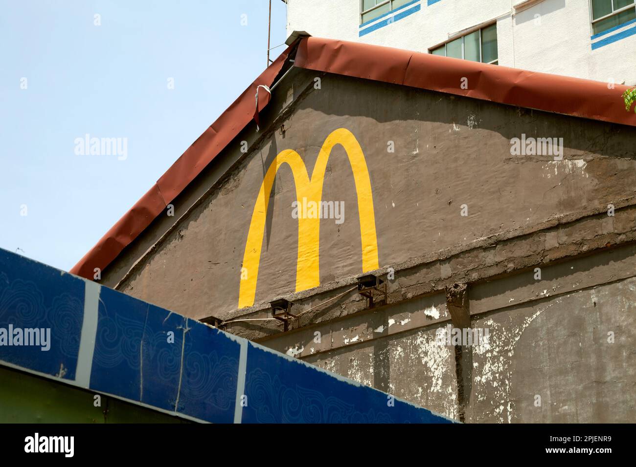 Ho Chi Minh ville, Vietnam - 28 mars 2023: Logo de McDonalds dessiné avec de la peinture jaune sur un vieux bâtiment laid. Restaurant de restauration rapide aux intempéries avec handma Banque D'Images