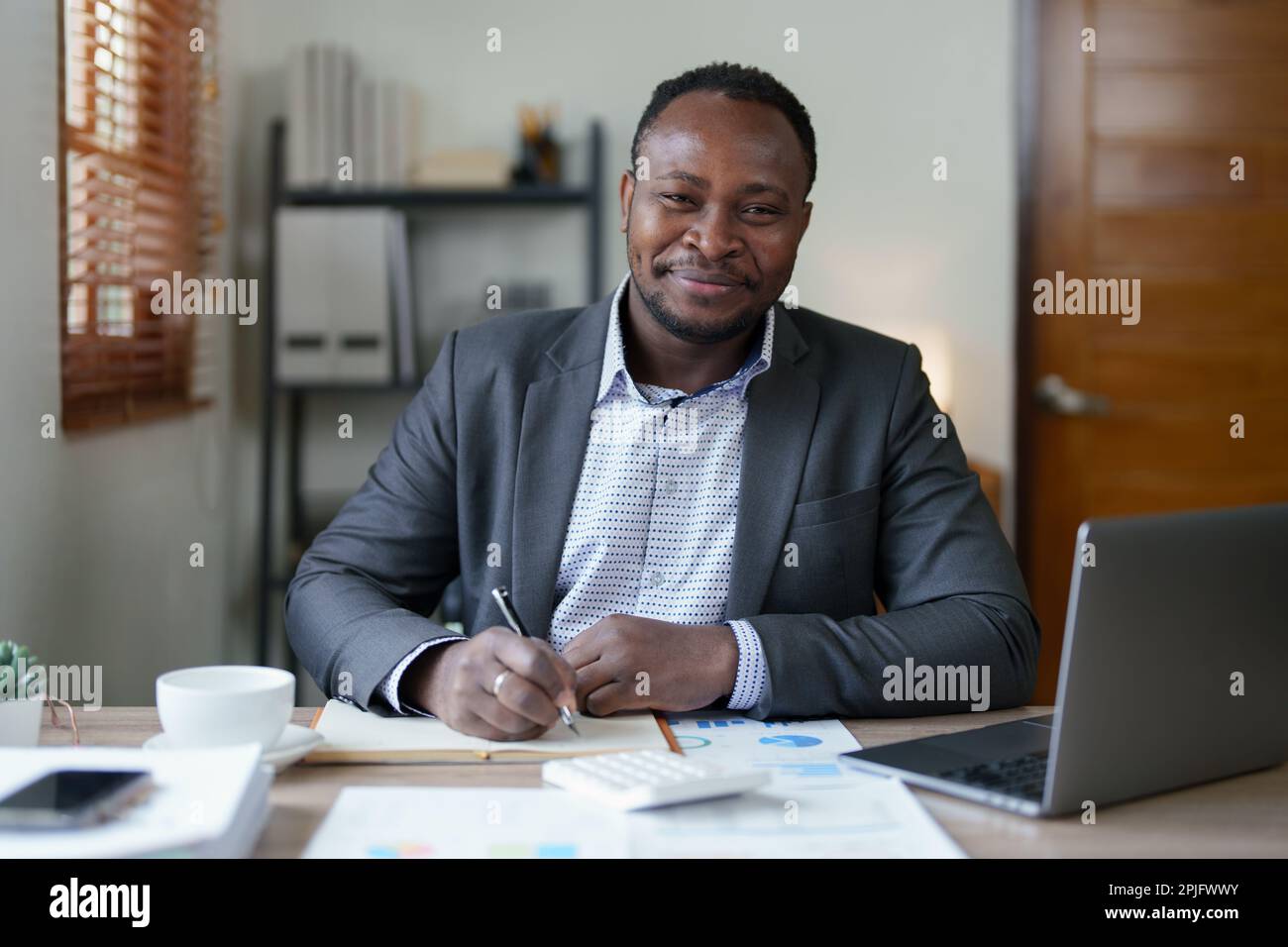 Homme d'âge moyen américain africain utilisant un ordinateur portable avec planification de travail sur les documents financiers, la fiscalité, les échanges, la comptabilité et conseiller financier Banque D'Images