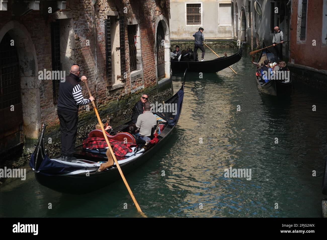 Les gondoliers bordent leurs gondoles avec des touristes à bord le long des canaux de Venise, Italie, 2 avril 2023 Banque D'Images