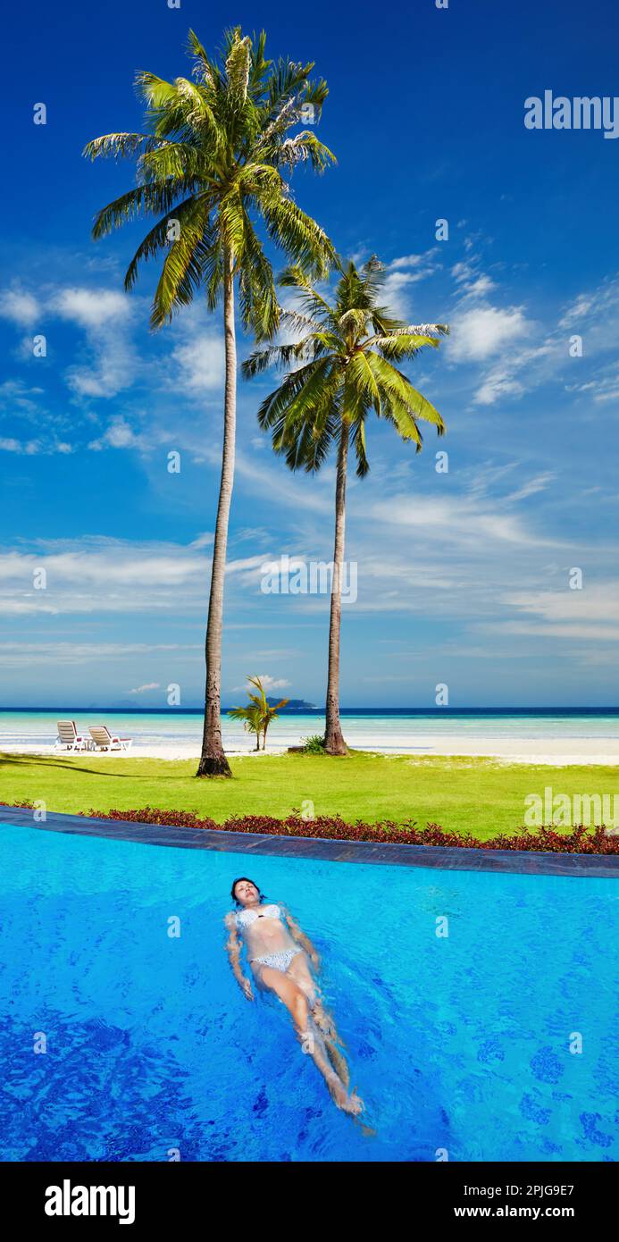 Femme dans la piscine à la plage tropicale Banque D'Images