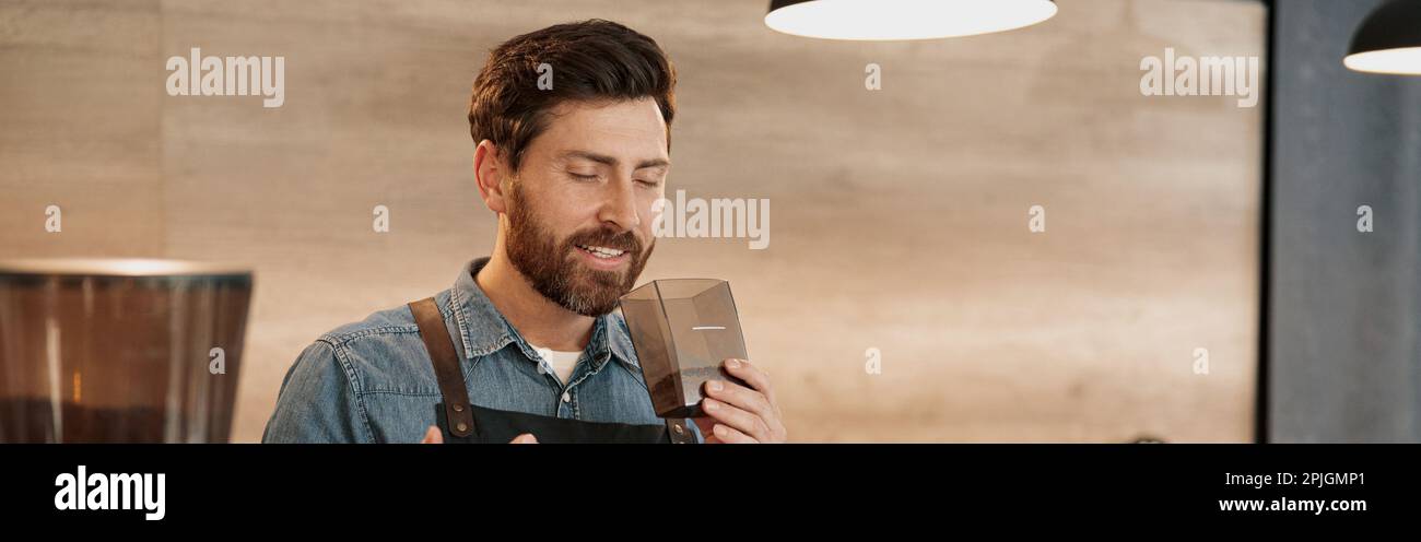 Le barista souriant apprécie l'arôme des grains de café à la cafétéria Banque D'Images