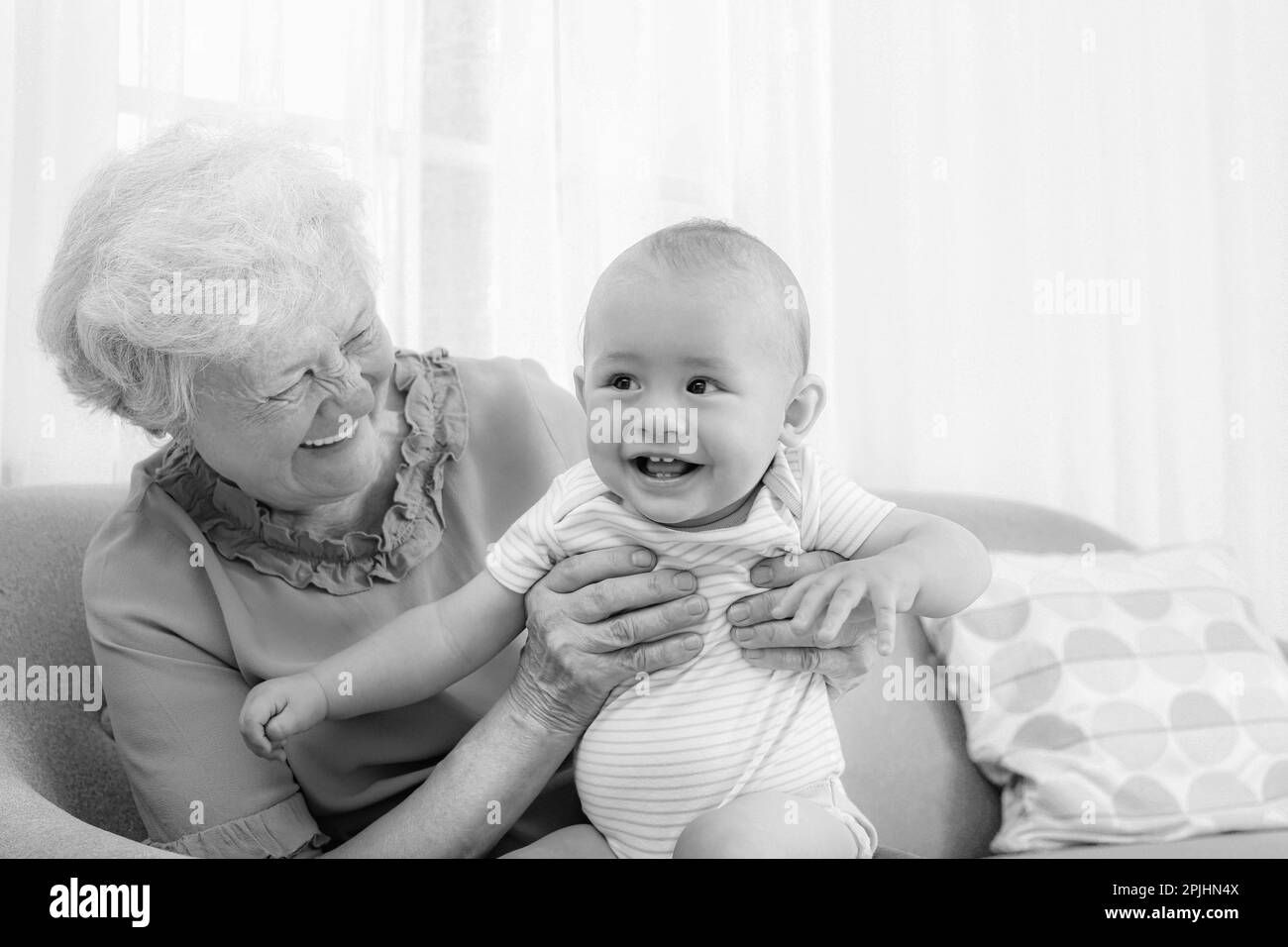 Une grand-mère heureuse avec un petit bébé à la maison. Photographie en noir et blanc Banque D'Images