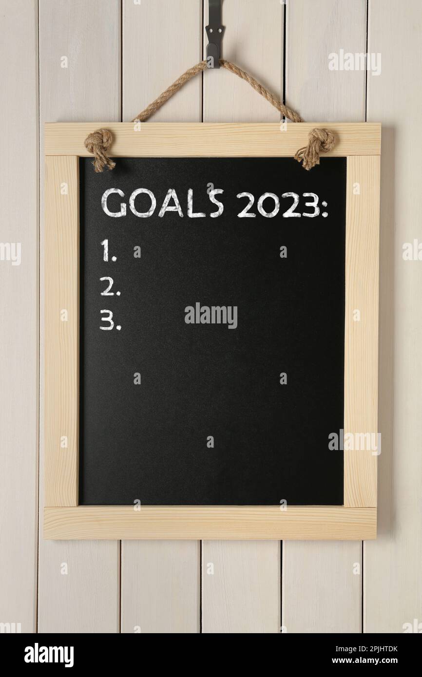 Tableau noir avec les buts de phrase 2023 et liste de contrôle vide sur l'accrochage sur fond blanc en bois Banque D'Images