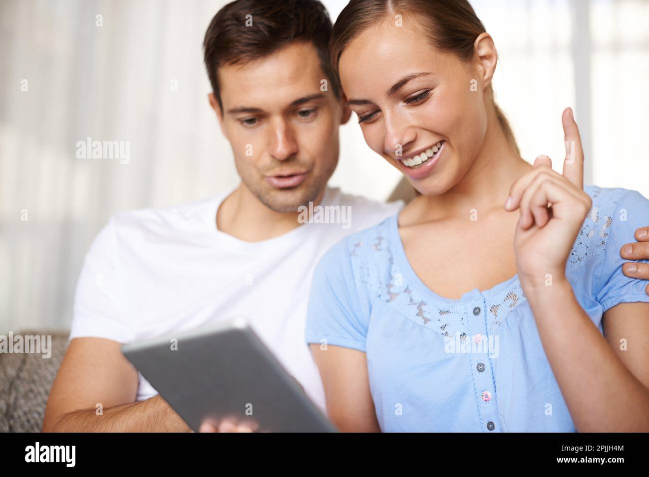 À mon tour de jouer. Un petit cliché d'un jeune couple heureux jouant à des jeux sur leur tablette. Banque D'Images