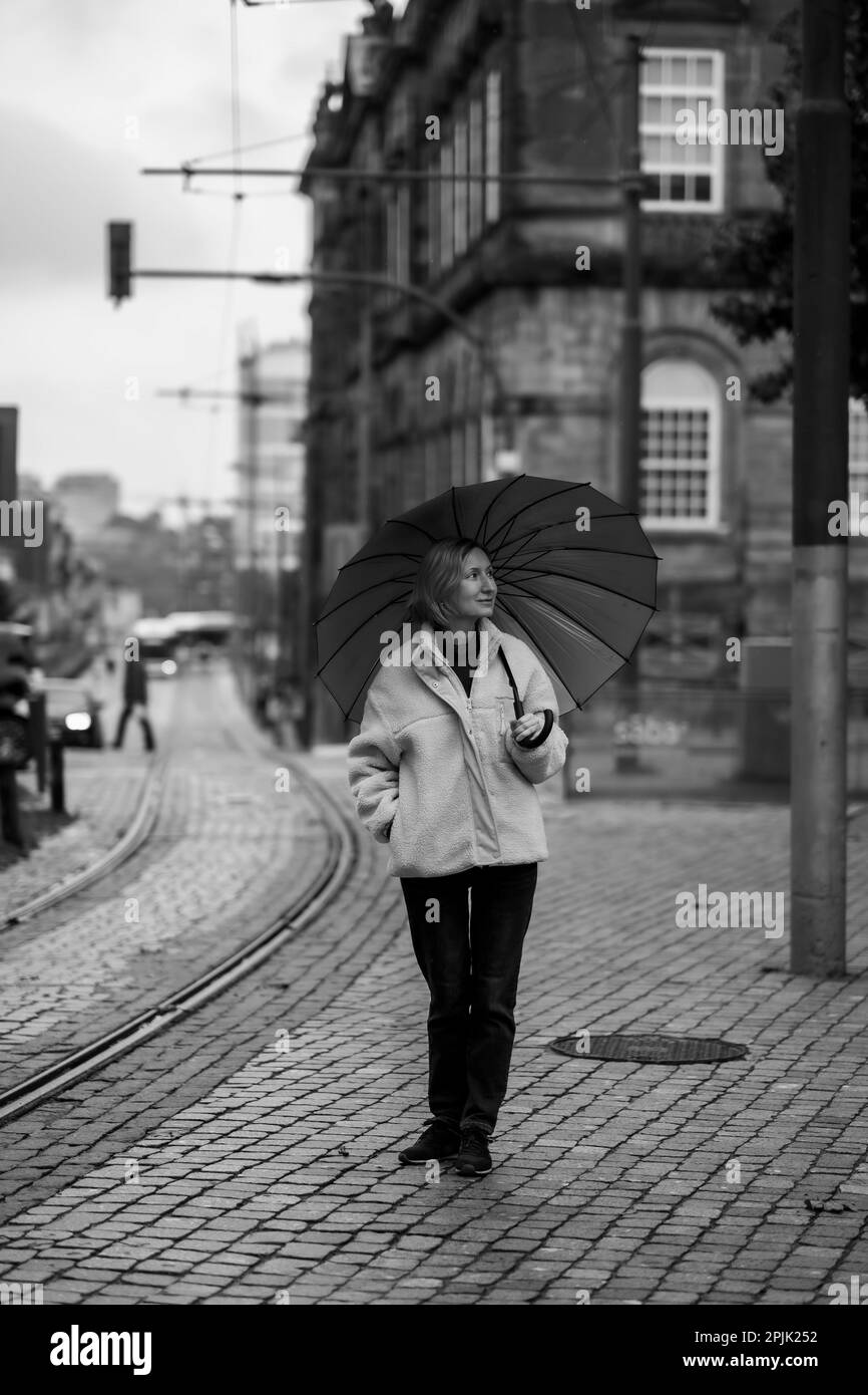 Une femme avec un parapluie marche dans la rue, Porto, Portugal. Photographie en noir et blanc. Banque D'Images
