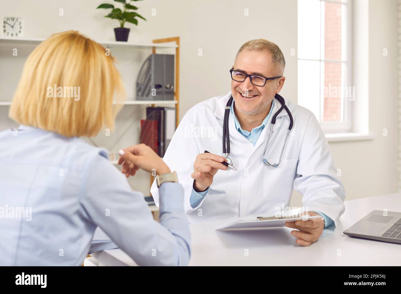 Un médecin senior heureux parle de quelque chose de drôle avec sa patiente Banque D'Images