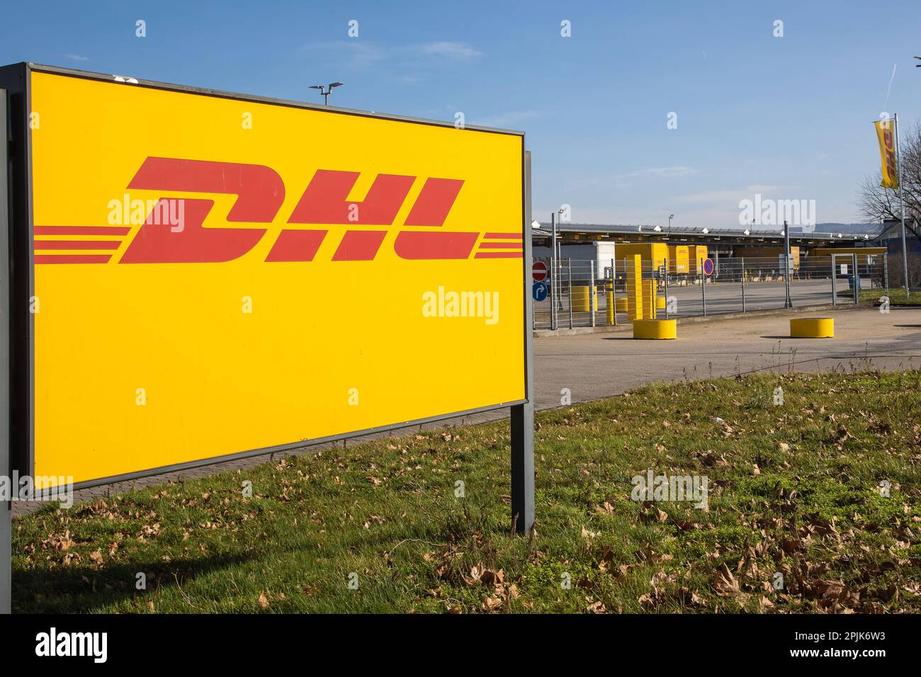 Koblenz, Allemagne - 20 février 2023: Label de société 'DHL' à l'entrée du centre de distribution local avec des camions devant le centre logistique Banque D'Images