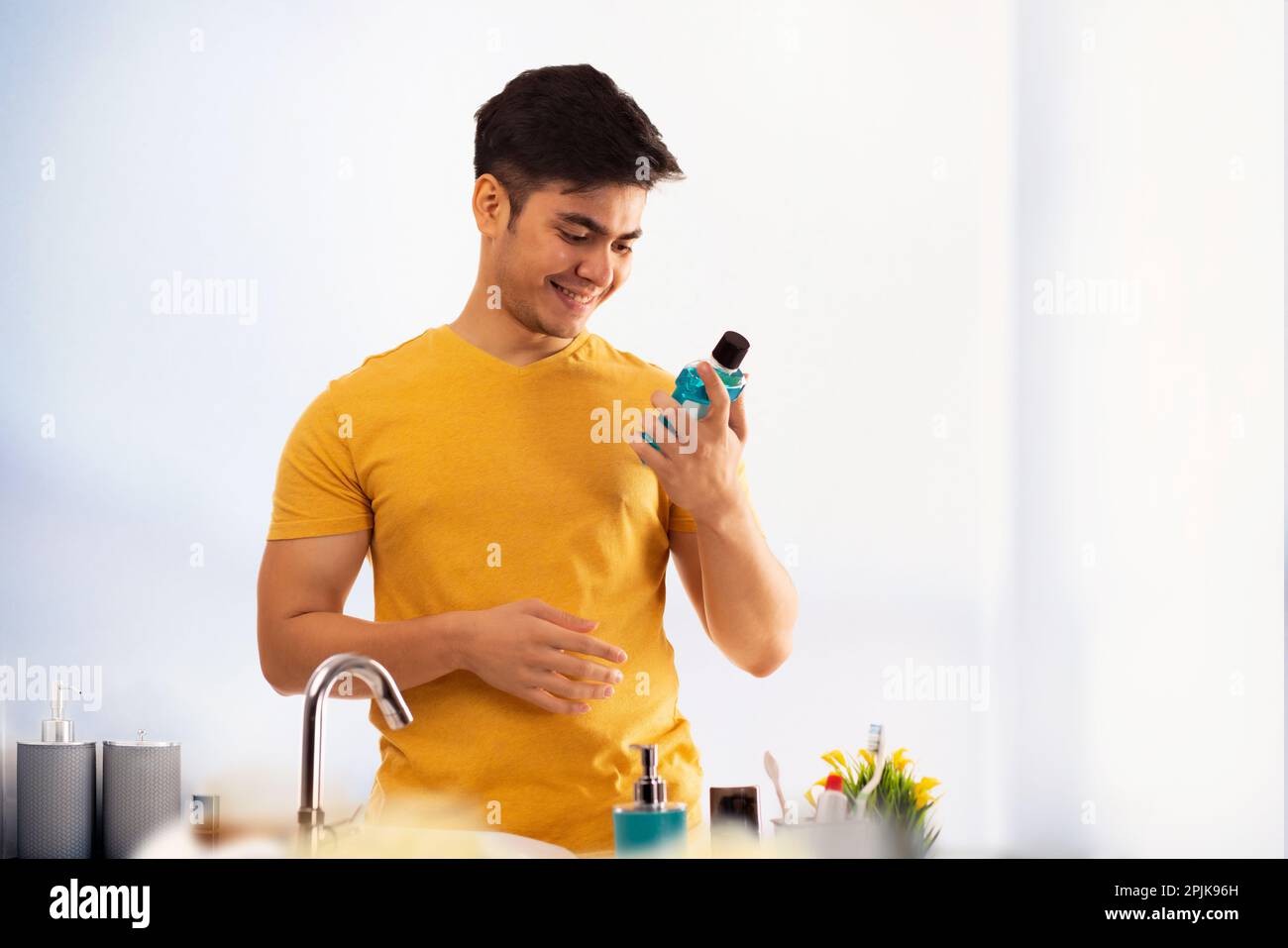 Jeune homme tenant une bouteille de bain de bouche dans sa main Banque D'Images