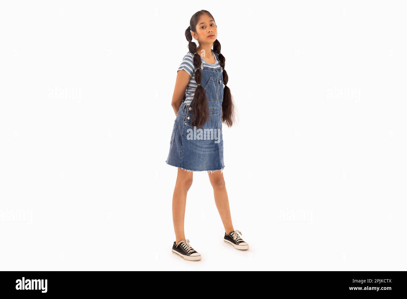 Tween fille avec des cheveux tressés debout sur fond blanc Banque D'Images