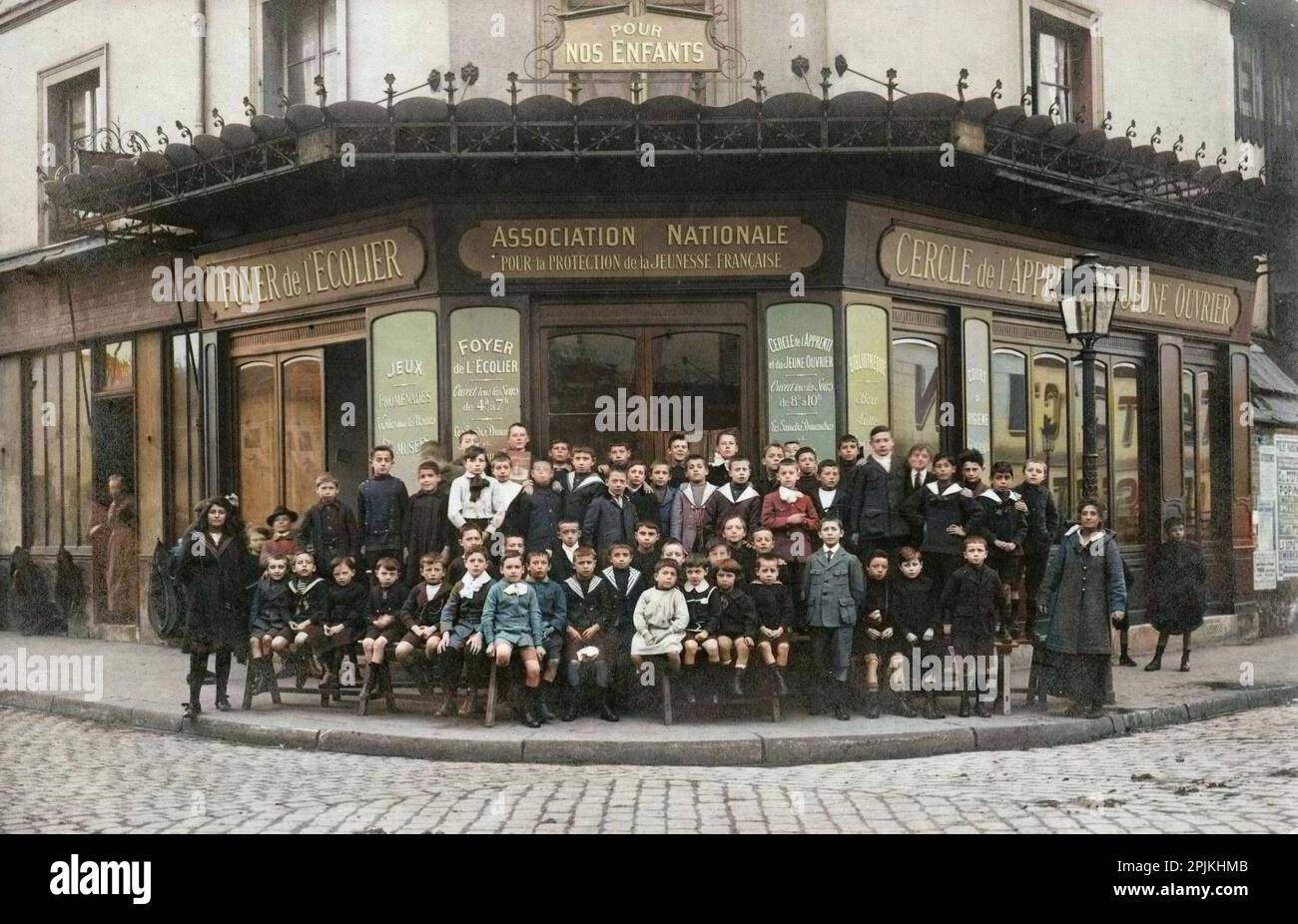 Les enfants du foyer de l'écolier et les jeunes étrangers sont apprentissages, regroups devant les locaux de l'Association nationale pour la protection de la Jeunesse française, à l'intersection de la rue Riquet et de la rue de Tanger, à Paris. Carte postale debut XXeme. Banque D'Images