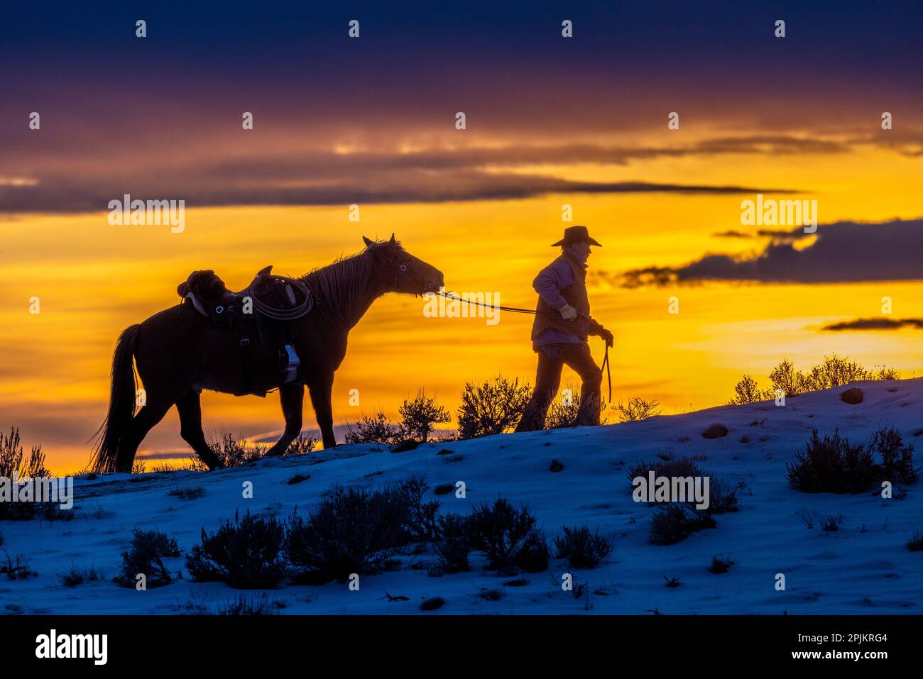 États-Unis, Wyoming. Hideout Horse Ranch, Wrangler et cheval au coucher du soleil. (MR,PR) Banque D'Images