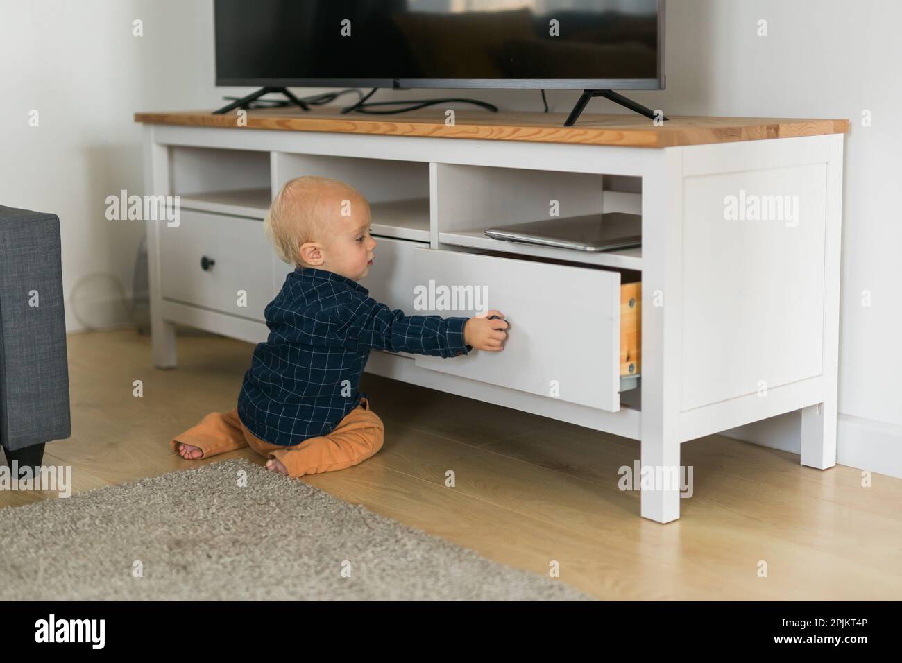 Tout-petit garçon ouvre le tiroir de l'armoire avec sa main. Enfant Explorer ce qui se trouve dans l'armoire. La curiosité du bébé et les étapes du développement de l'enfant Banque D'Images