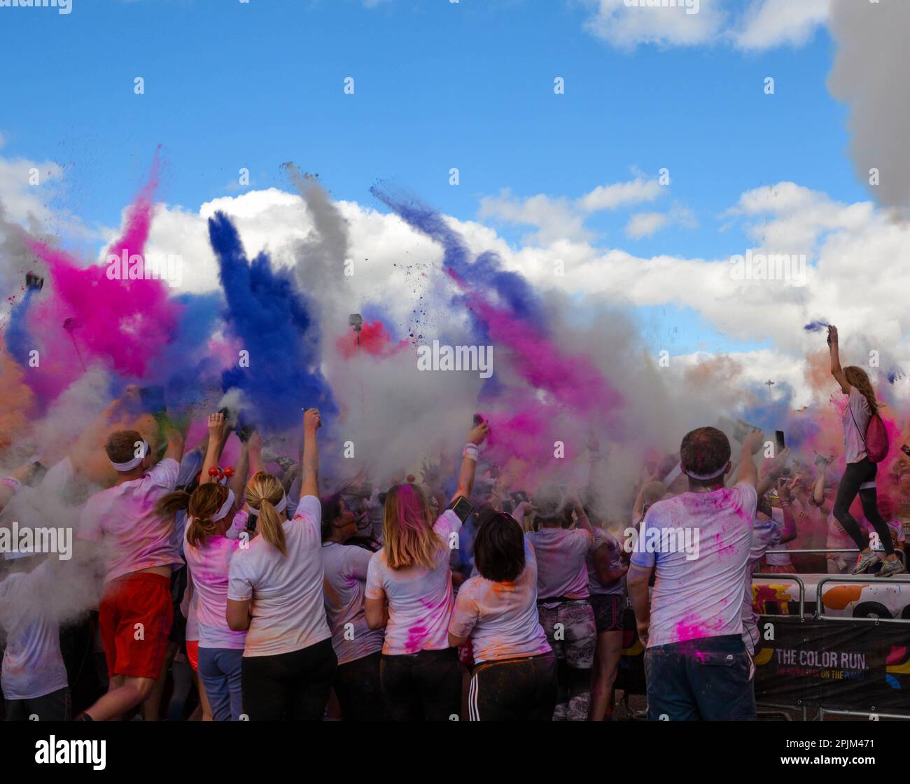 Groupe de coureurs à Color Run à Birmingham, Angleterre, Royaume-Uni, célébrant à la fin de la course en jetant de la poudre de peinture colorée Banque D'Images