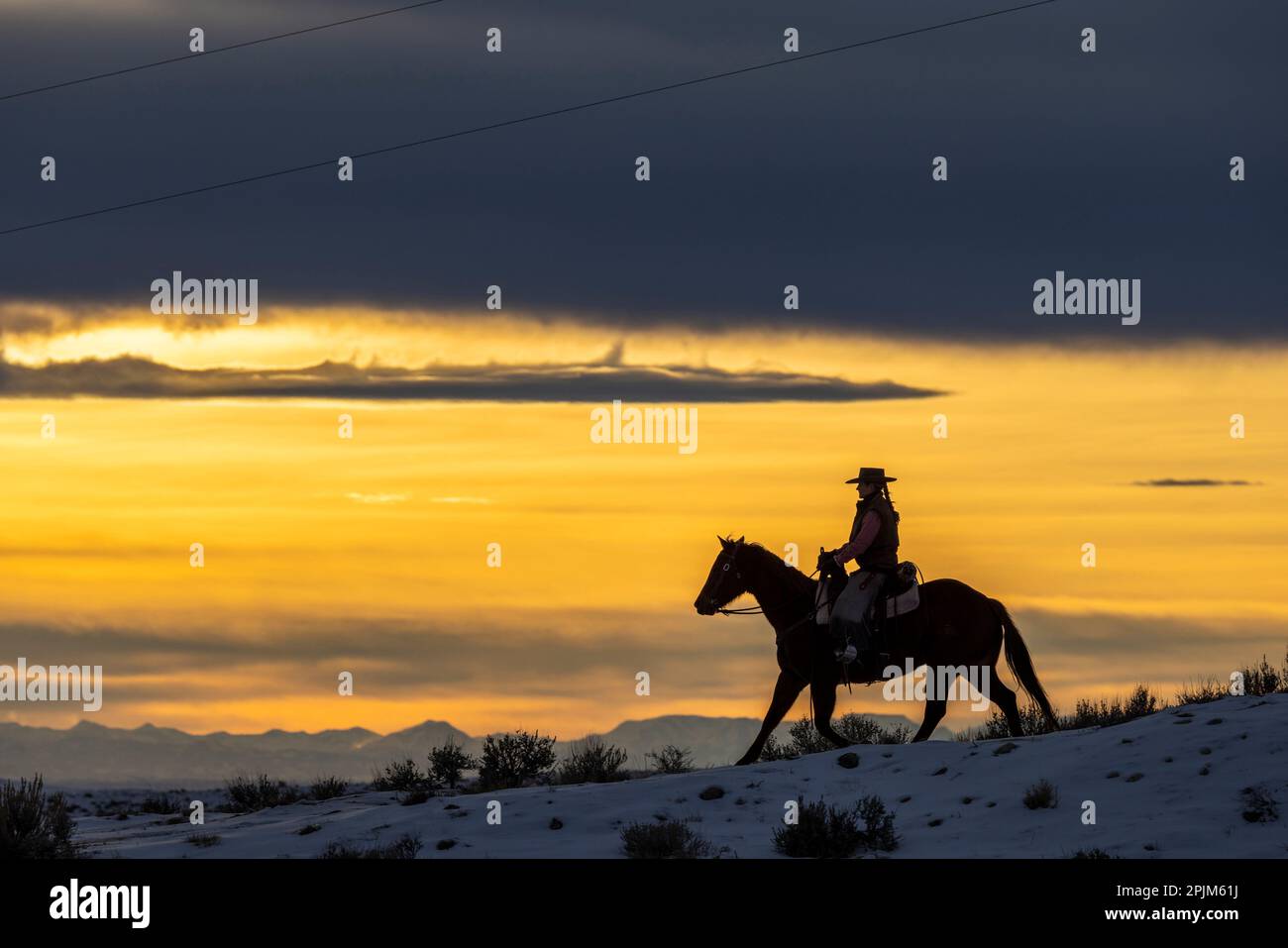 États-Unis, Wyoming. Hideout Horse Ranch, Wrangler et cheval au coucher du soleil. (MR,PR) Banque D'Images