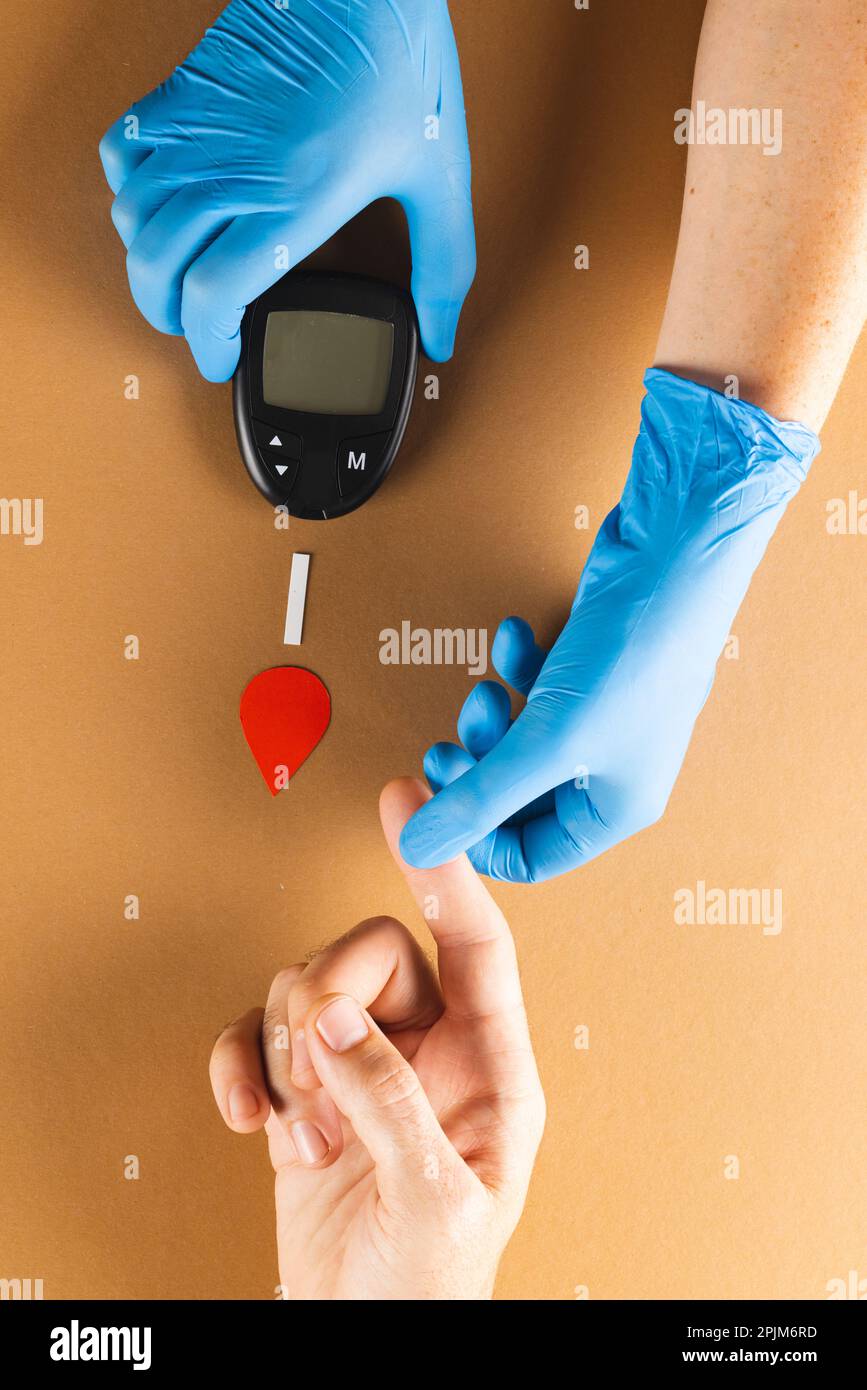 Mains du médecin ganté avec glucomètre prenant la lecture de sucre de sang de la femme caucasienne Banque D'Images