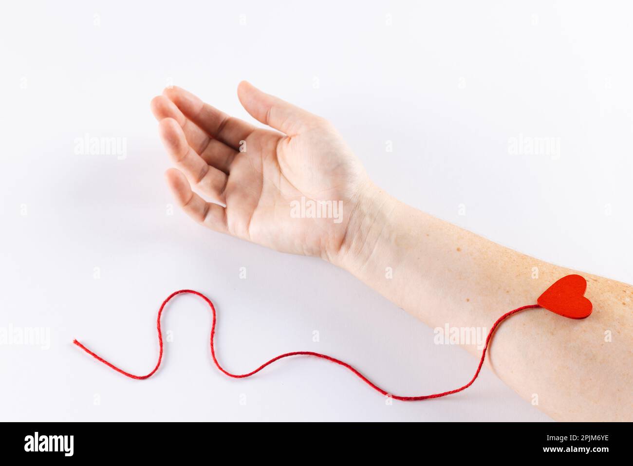 Bras de femme caucasienne avec coeur et fil rouge, sur fond blanc Banque D'Images