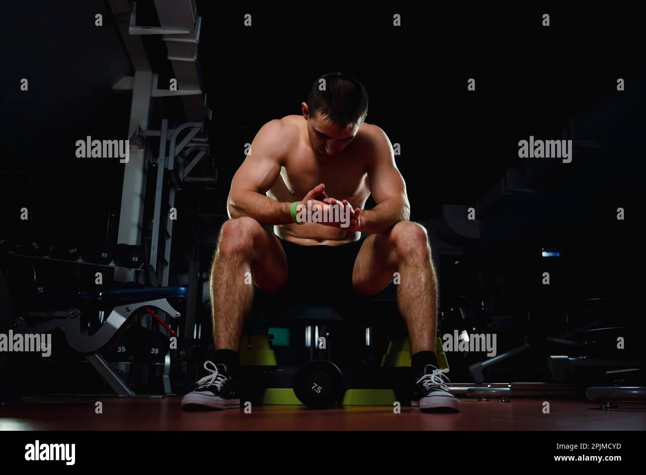 Beau jeune homme regardant vers l'avant après un cours d'exercice à la  salle de gym sombre. Musculation, musculation, sport Photo Stock - Alamy