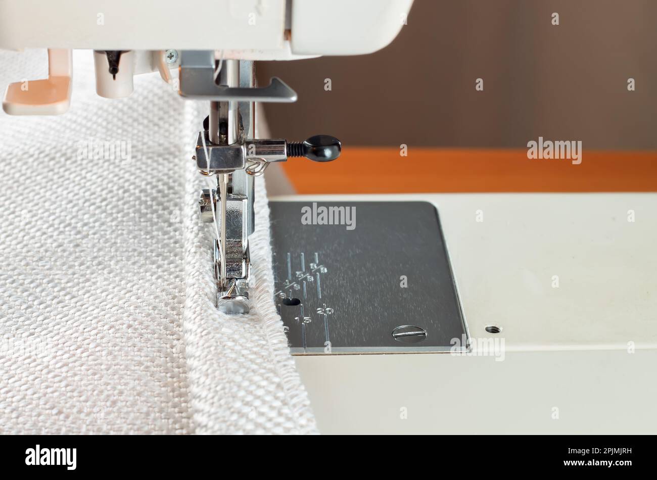 Machine à coudre moderne, plus près du pied. le processus de couture d'une bordure décorative de tissu blanc. Banque D'Images