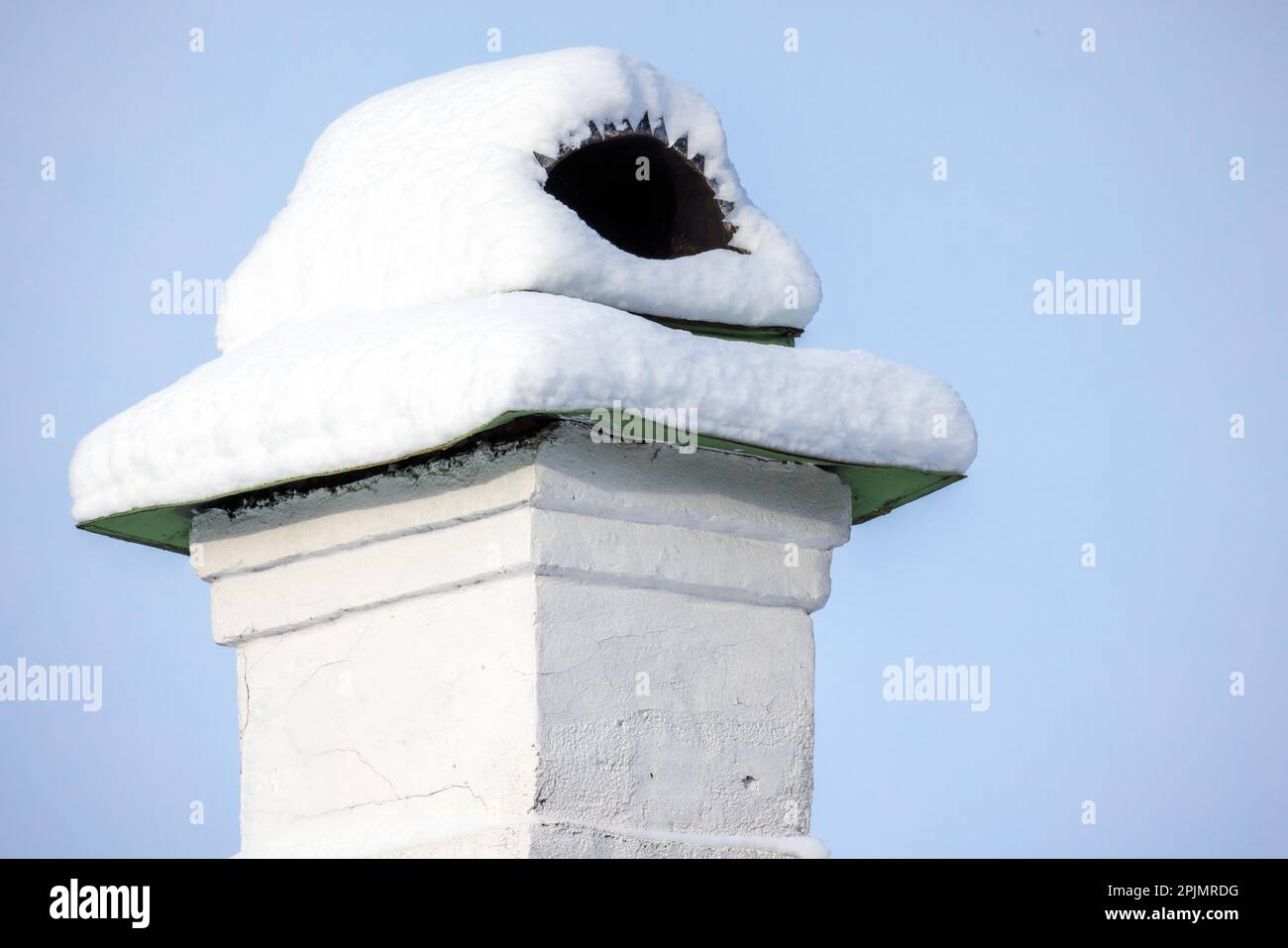 Une cheminée avec de la neige sur le toit d'une maison rurale est sous le ciel bleu un jour d'hiver, photo de gros plan Banque D'Images