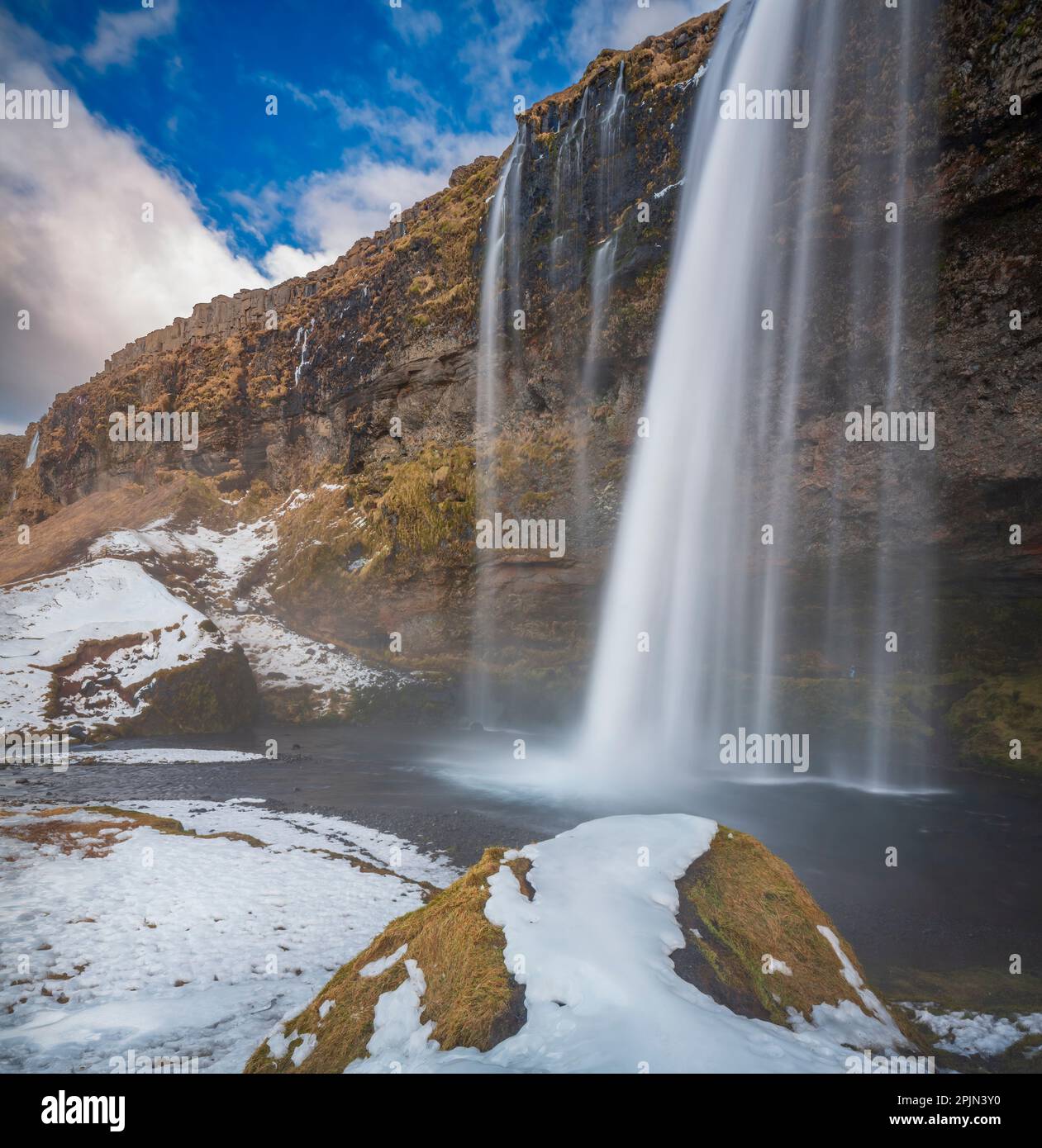 Vue sur Seljalandsfoss depuis l'intérieur de la cascade lors d'une belle journée d'hiver, en Islande. Banque D'Images