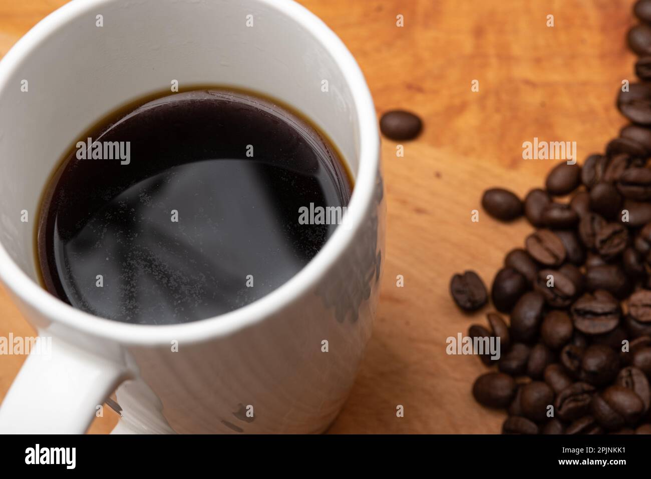Café noir avec grains de café sur le côté d'une planche à bois Banque D'Images