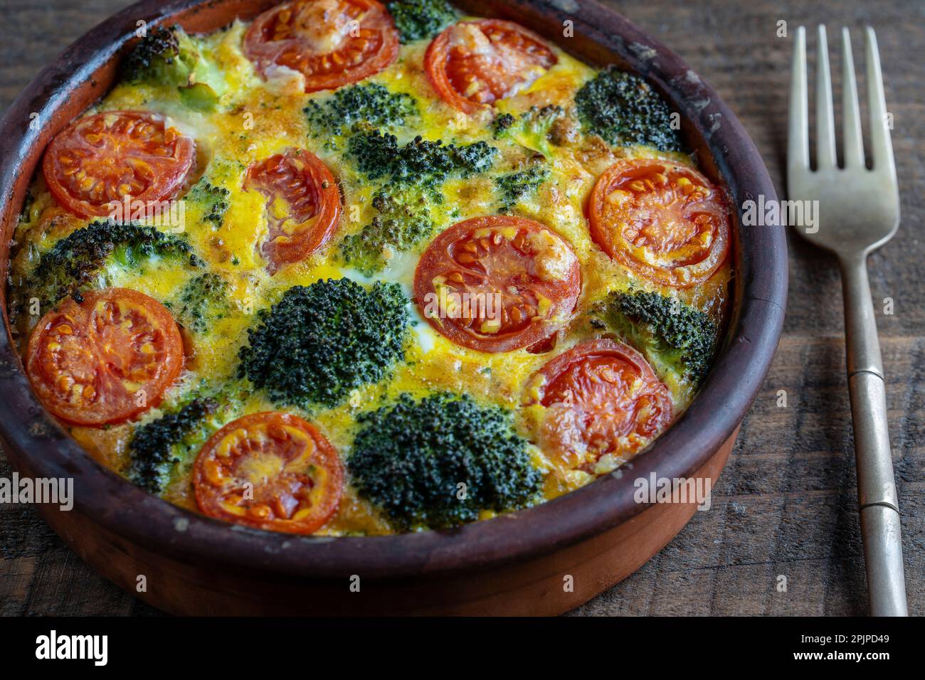 Frittata aux légumes avec bol en céramique, la nourriture végétarienne simple. La Frittata avec des œufs, de la tomate, le poivron, l'oignon, le brocoli et fromage,. Banque D'Images