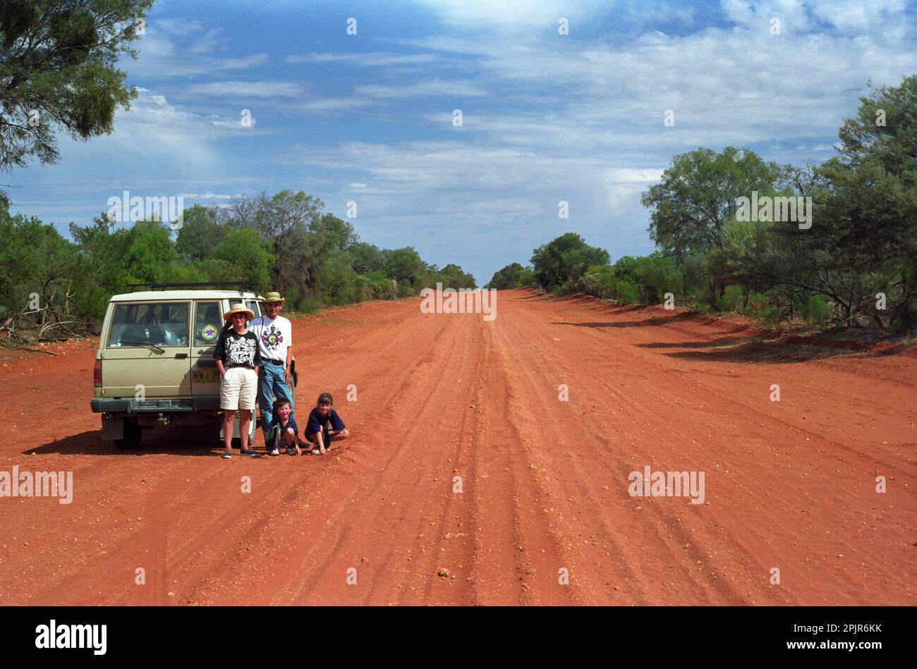 Route de la poussière rouge, The Cut Line, alias Wanaaring Road, entre Wanaaring et Gumbalie, dans l'Outback de la Nouvelle-Galles du Sud, Australie : la famille pose par leur Holden Jackaroo 4WD Banque D'Images