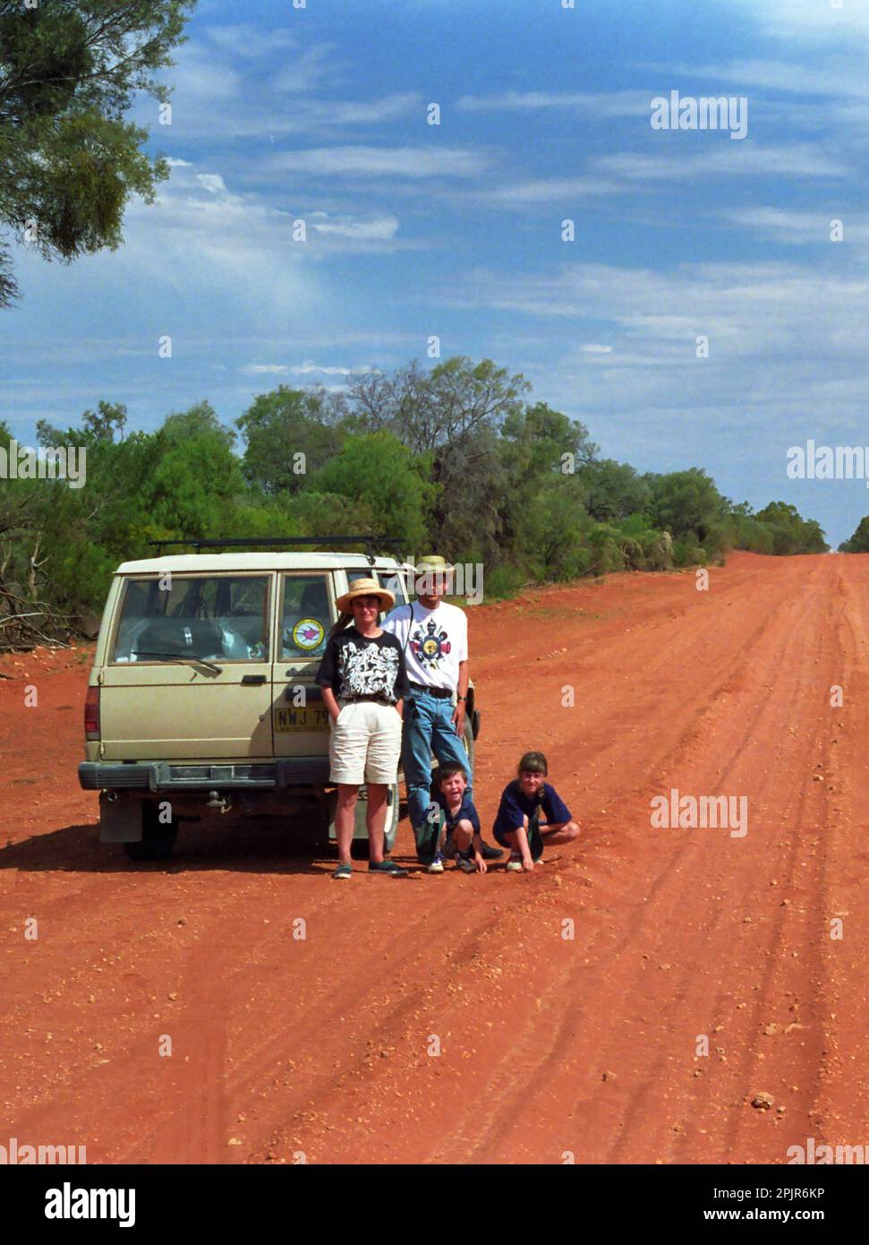 Route de la poussière rouge, The Cut Line, alias Wanaaring Road, entre Wanaaring et Gumbalie, dans l'Outback de la Nouvelle-Galles du Sud, Australie : la famille pose par leur Holden Jackaroo 4WD Banque D'Images